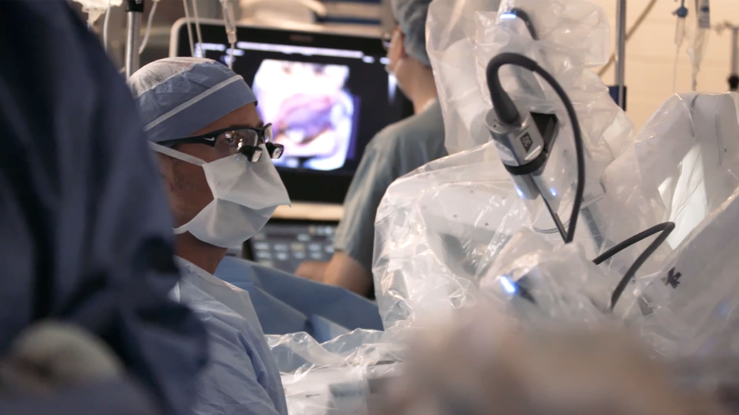 A surgeon monitors the arms of a robotic surgery system during a cardiac surgery procedure.
