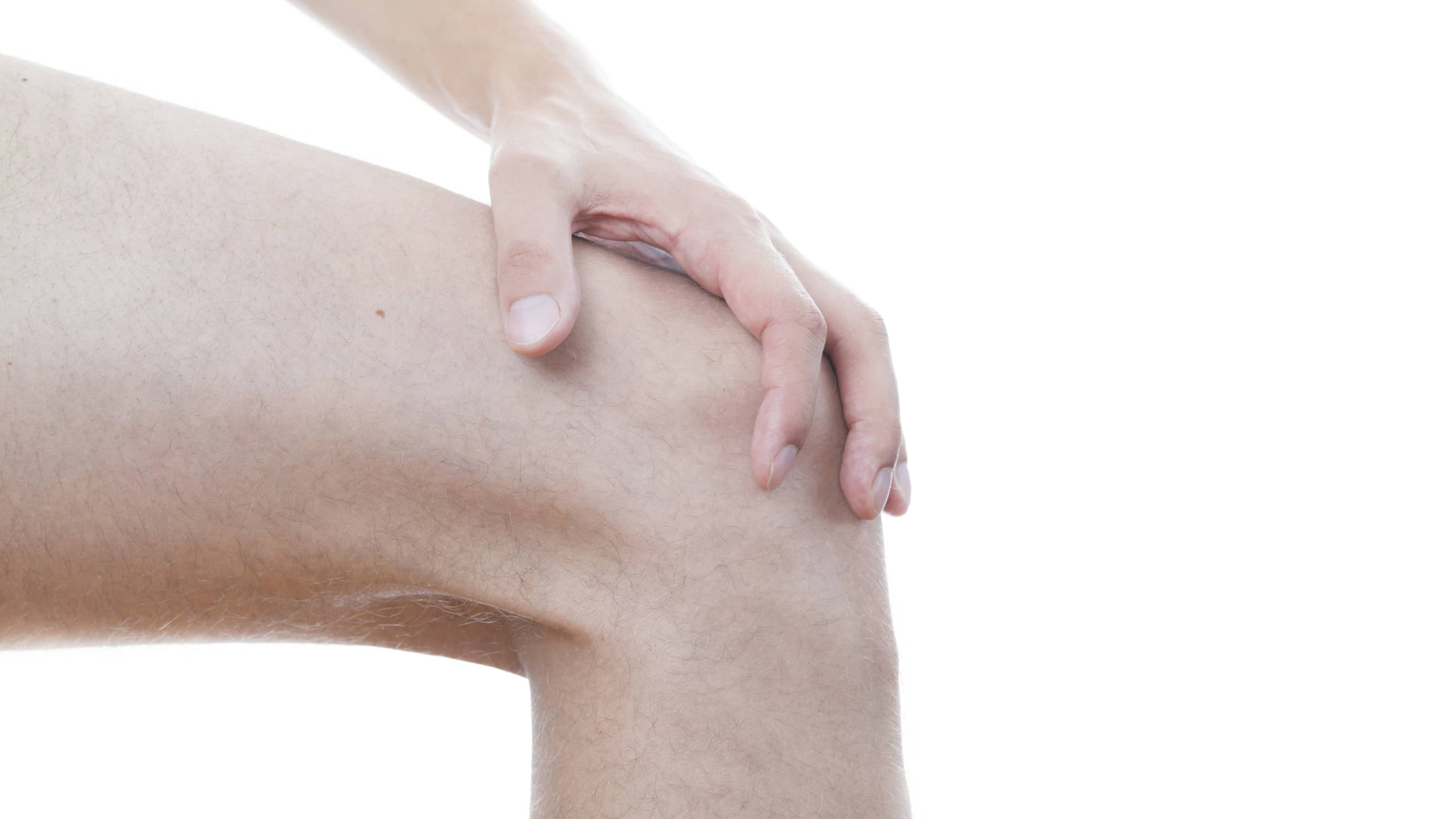 A hand itches the top of a bare knee, possibly because of eczema