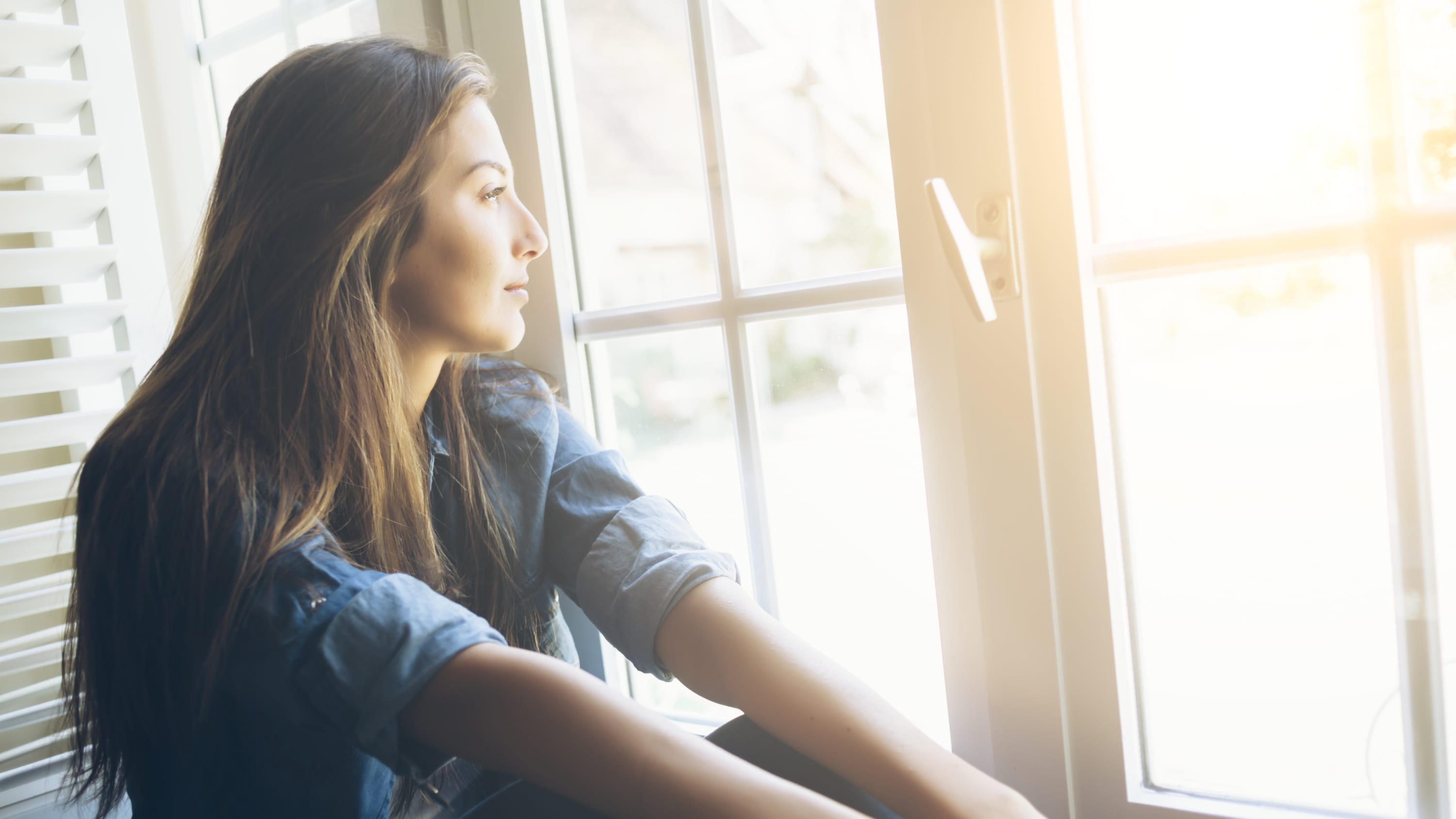 woman looking out window thinking about fertility preservation
