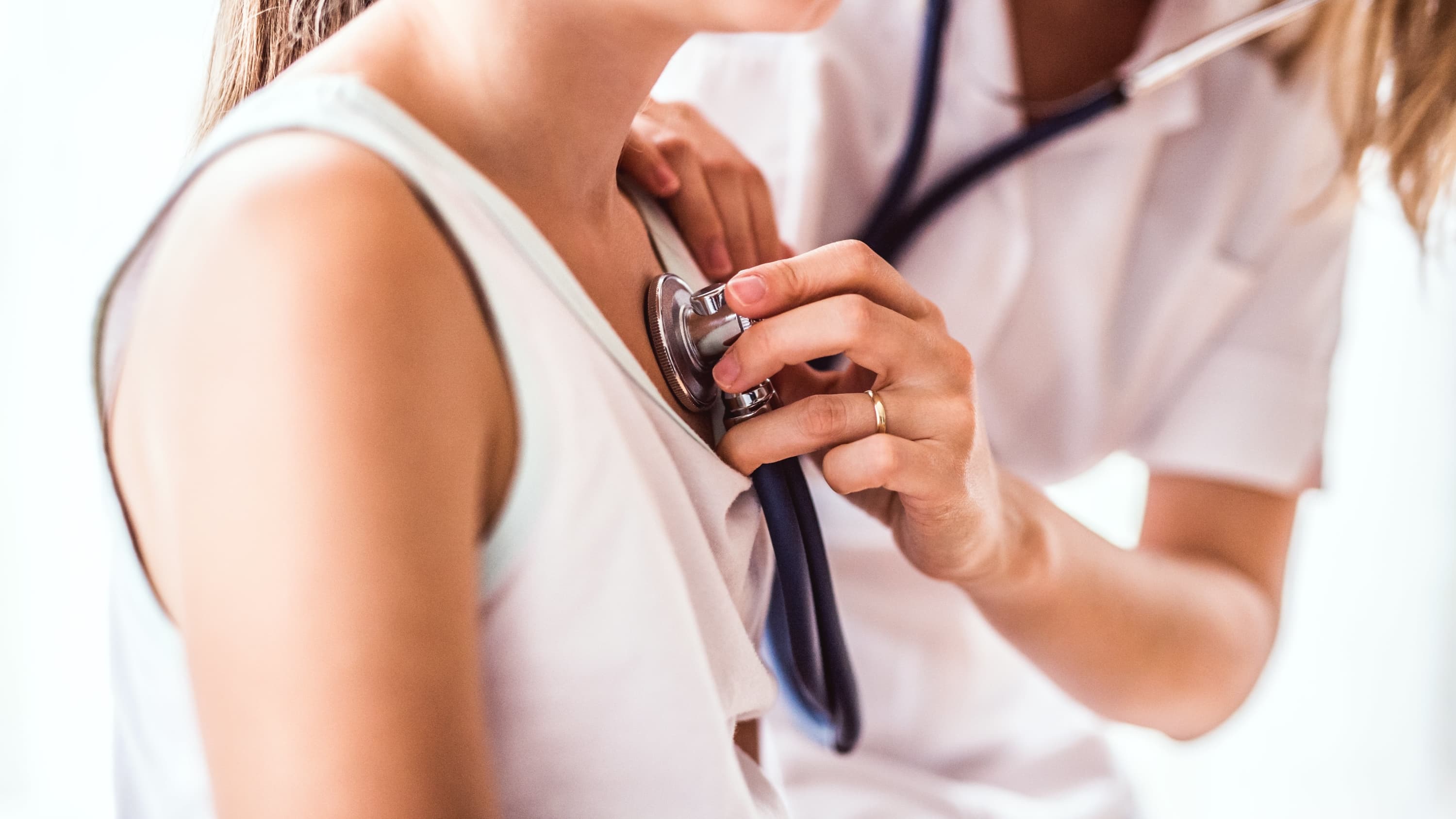 doctor placing stethescope on young girl's chest, looking for heart murmur
