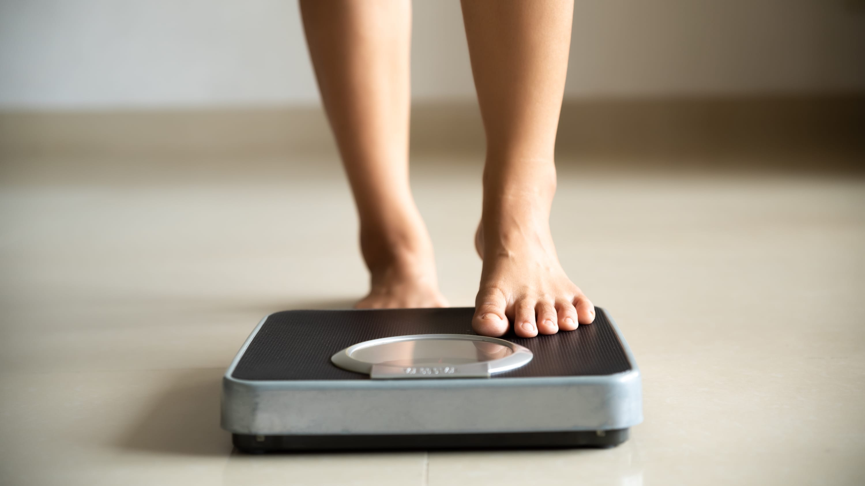 woman stepping on the scale, hoping for weight loss