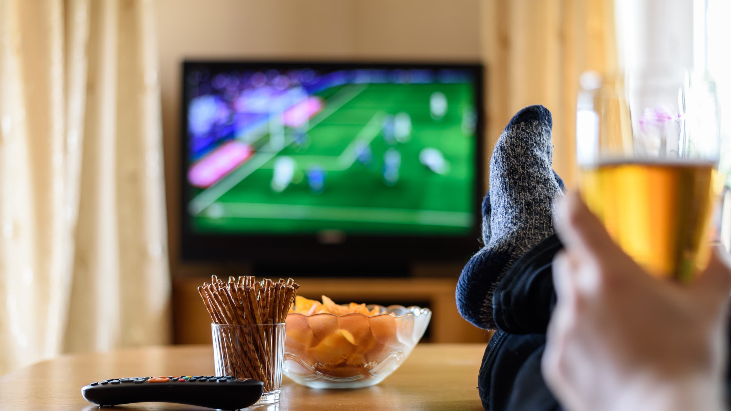 person watching TV with a beer and chips, possibly at risk for prediabetes