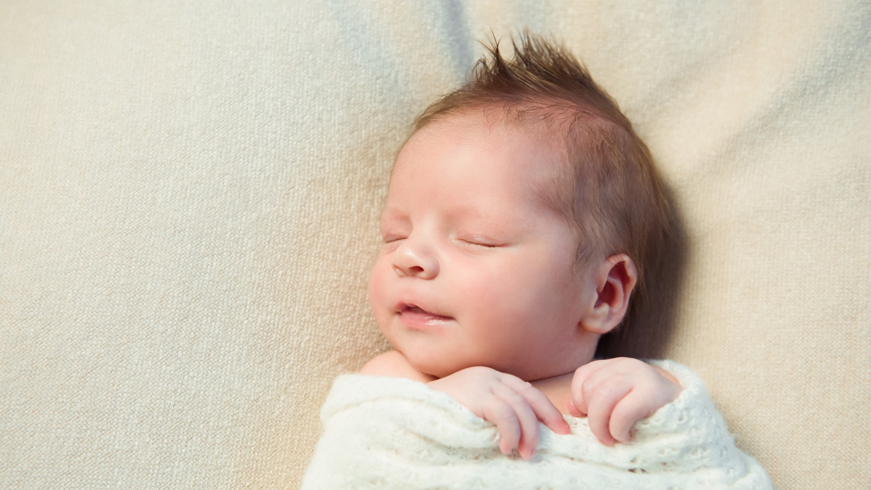 a newborn, possibly conceived through methods for transgender individuals, sleeps.