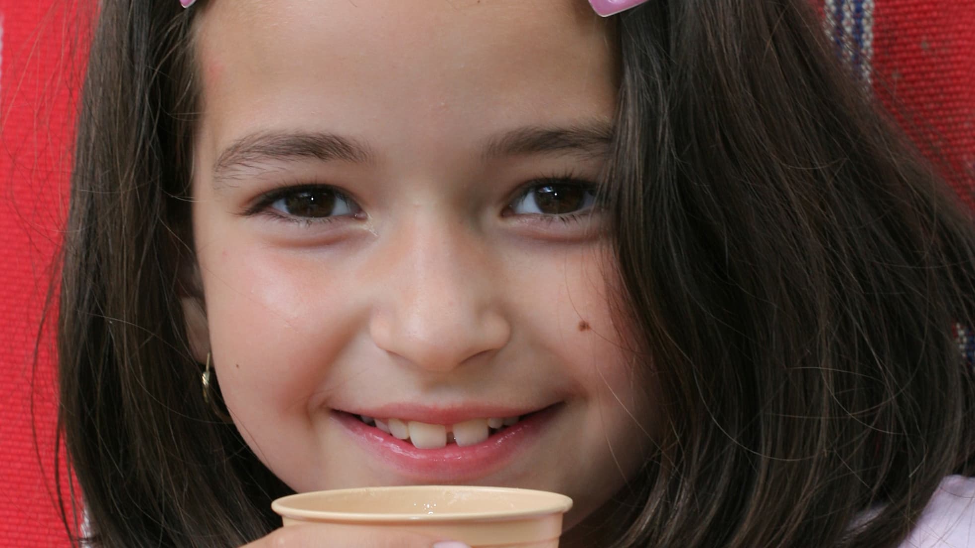 A girl who may have a congenital hand condition holds a cup.