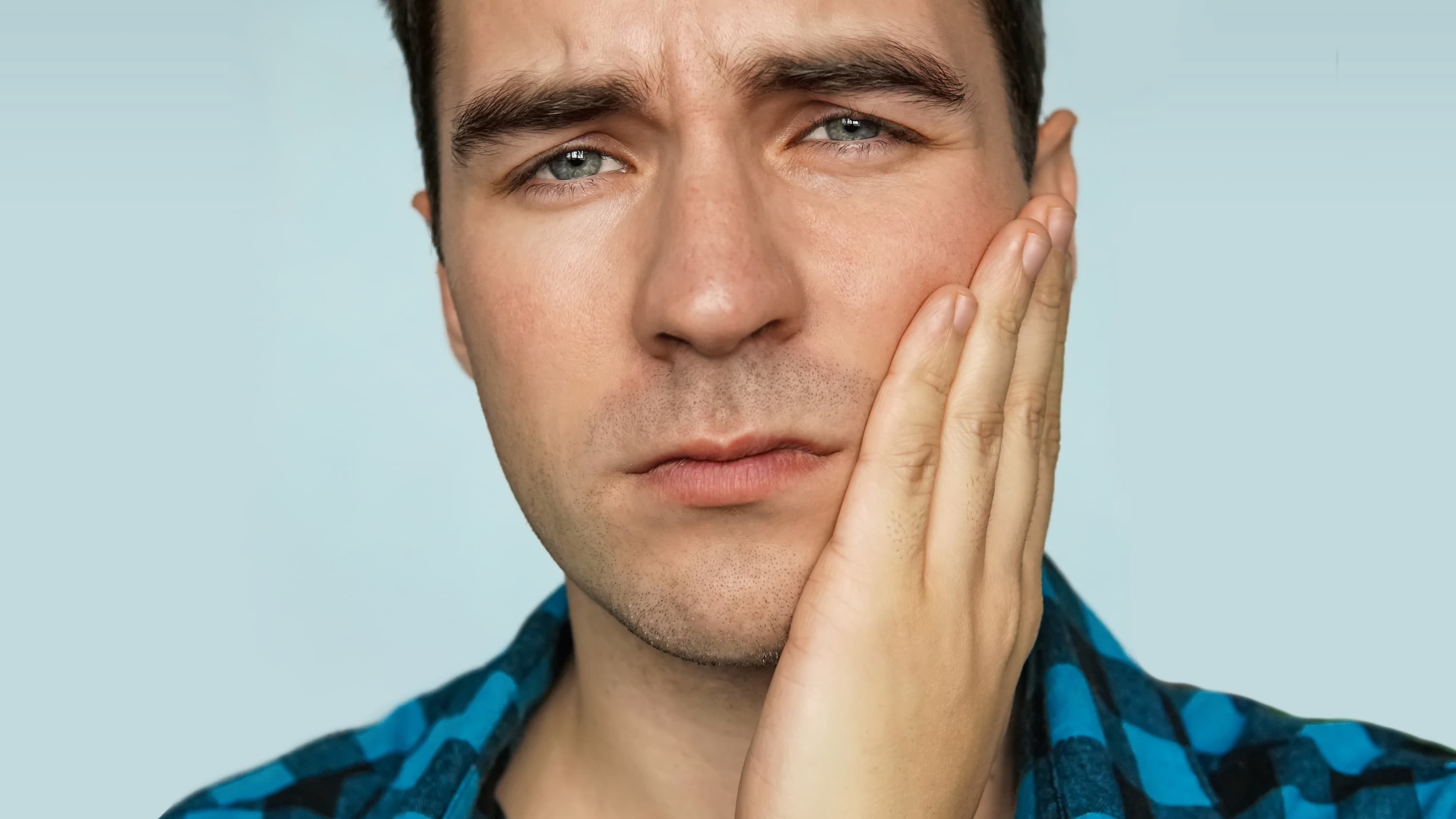 A man with trigeminal neuralgia touching his jaw who is in pain.