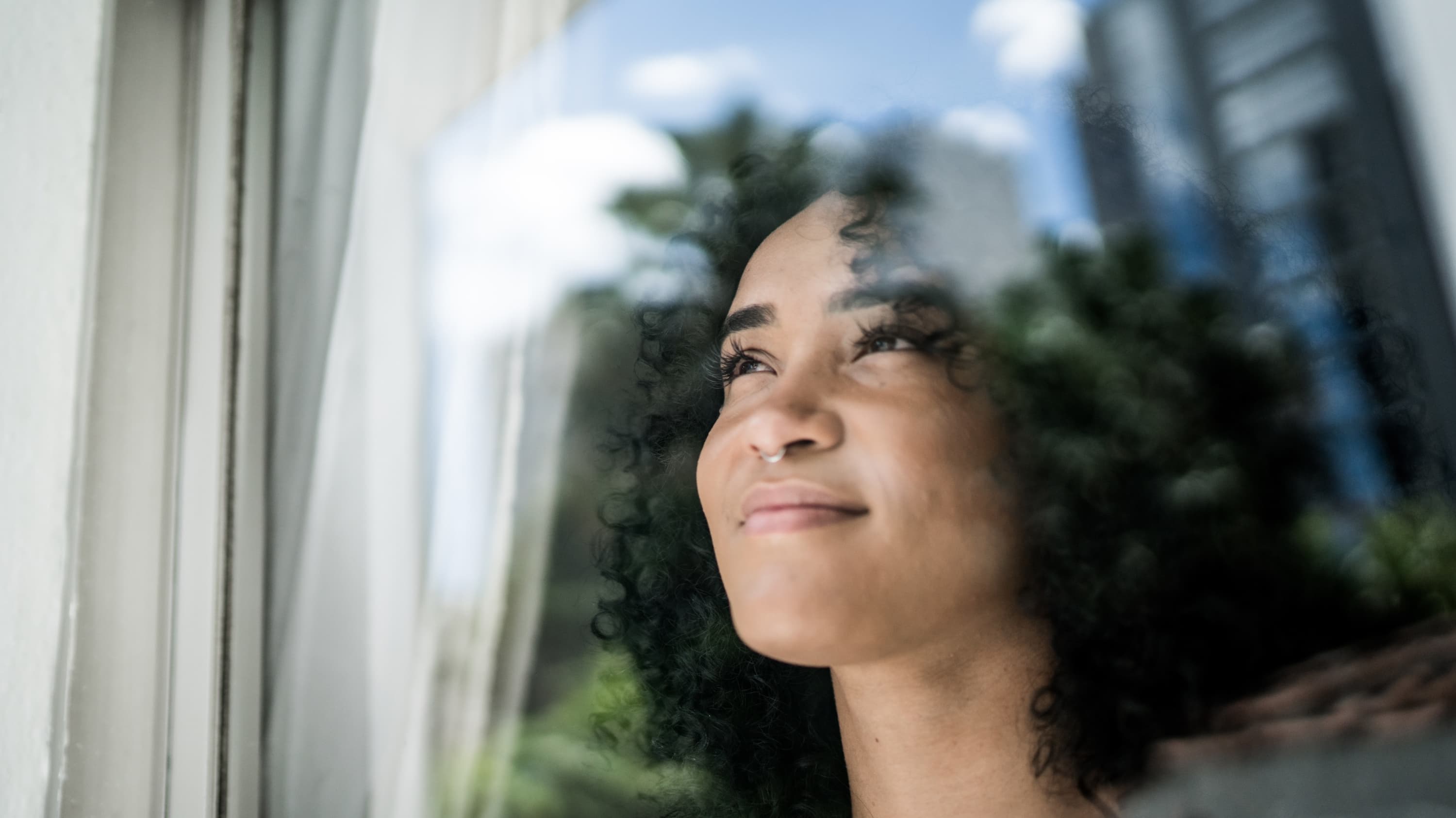 woman looking out window after thyroid cancer treatment