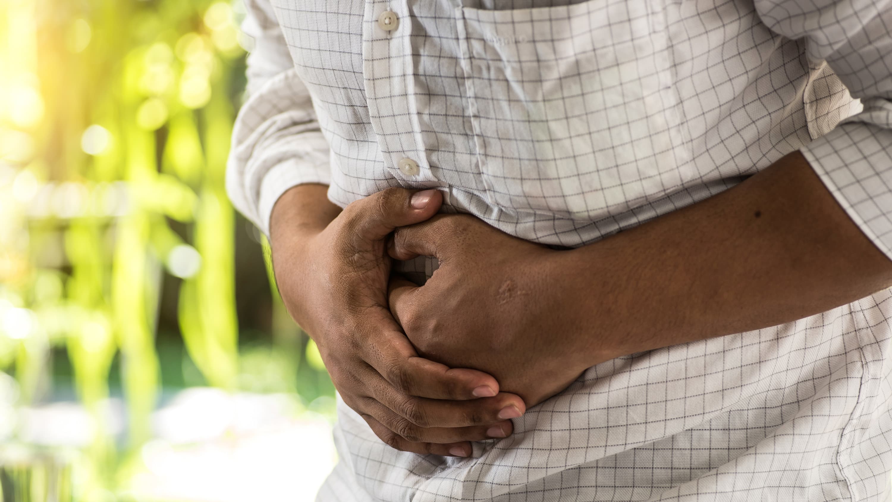 A man, in pain, touches his stomach. He may be experiencing abdominal migraine.