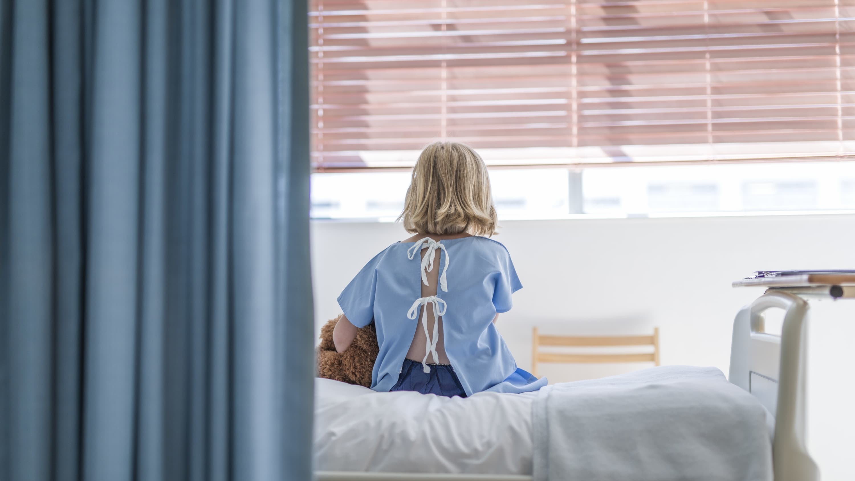 kid, possibly with hepatitis diagnosis, wearing a hospital gown on a hospital bed