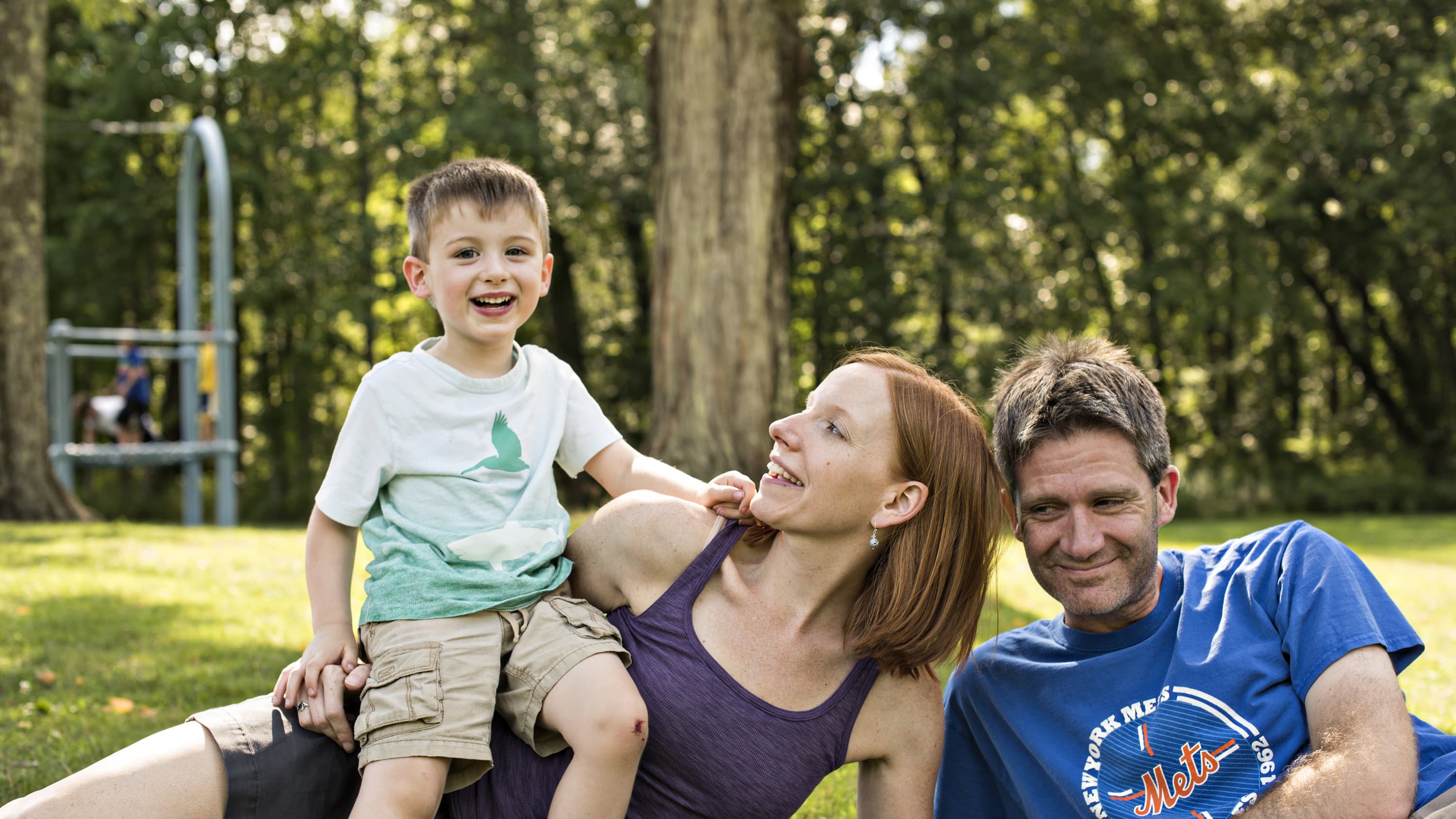 A young boy, Zachary Bailey, poses in a park with his parents, Carrie MacMillan and Hugh Bailey.