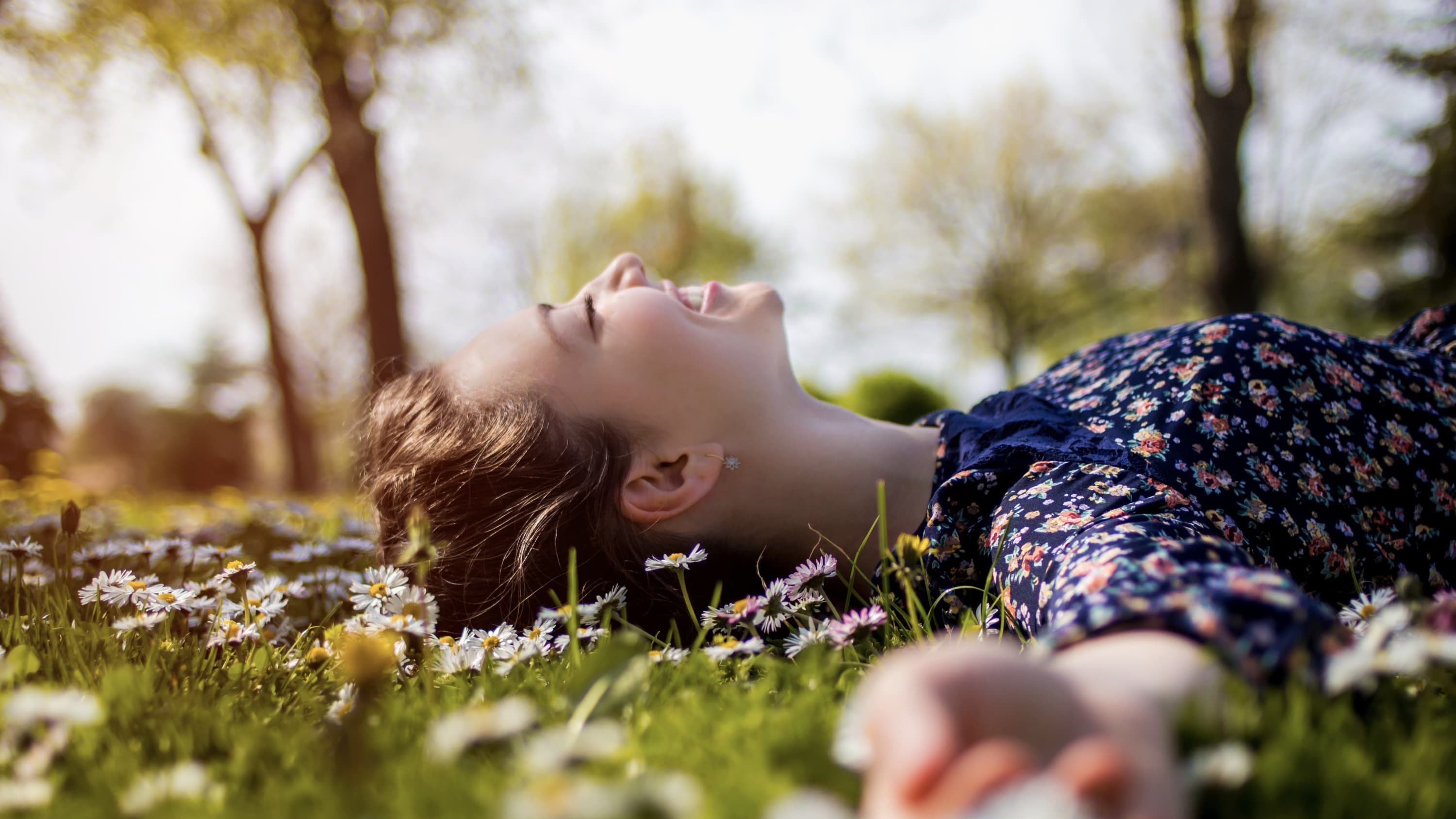 happy teenager lying in grass, possibly because of promising trial results for the Pfizer-BioNTech vaccine in adolescents