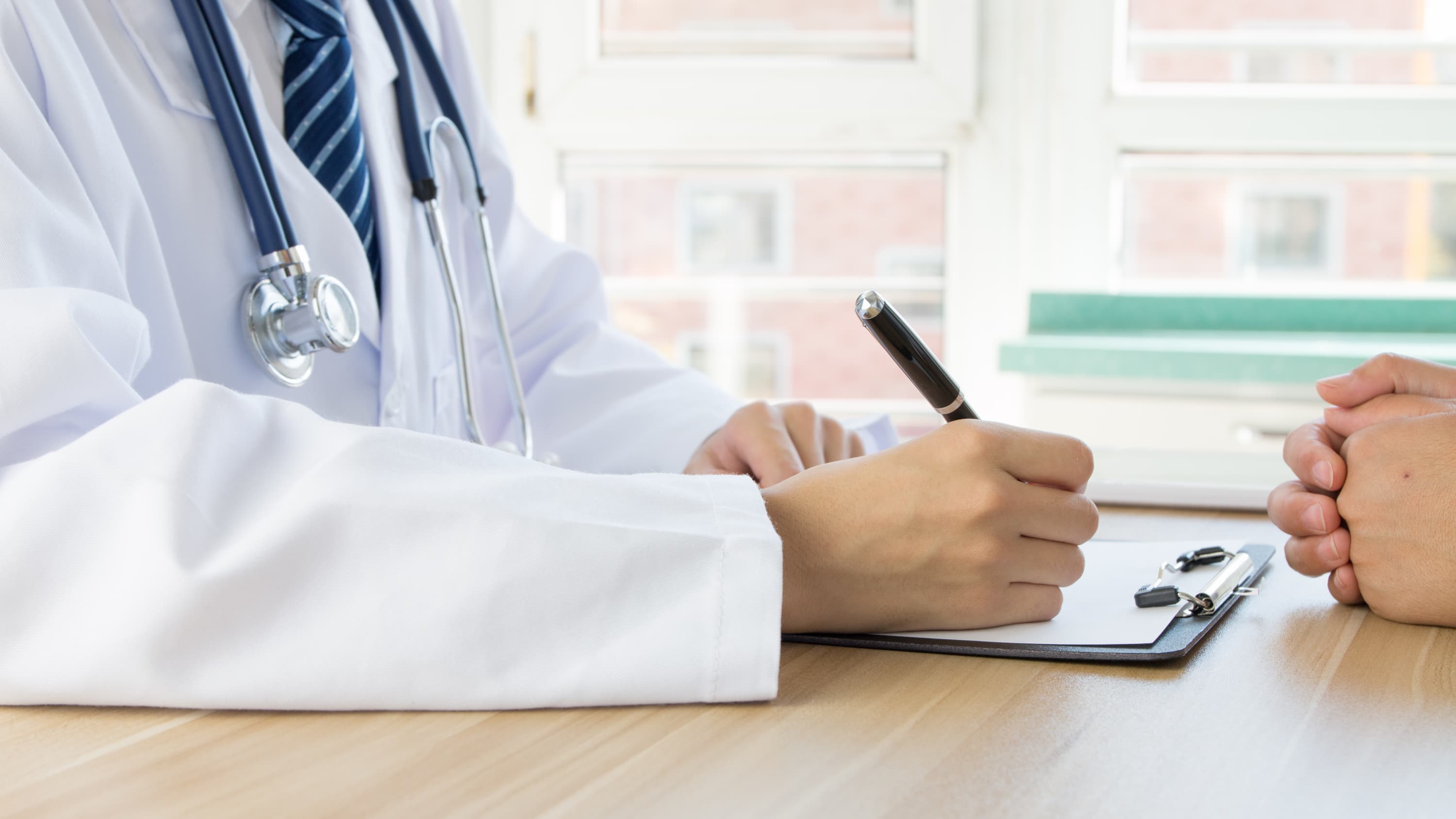 .A doctor writes notes for a patient, one possibly with Hepatitis B or C