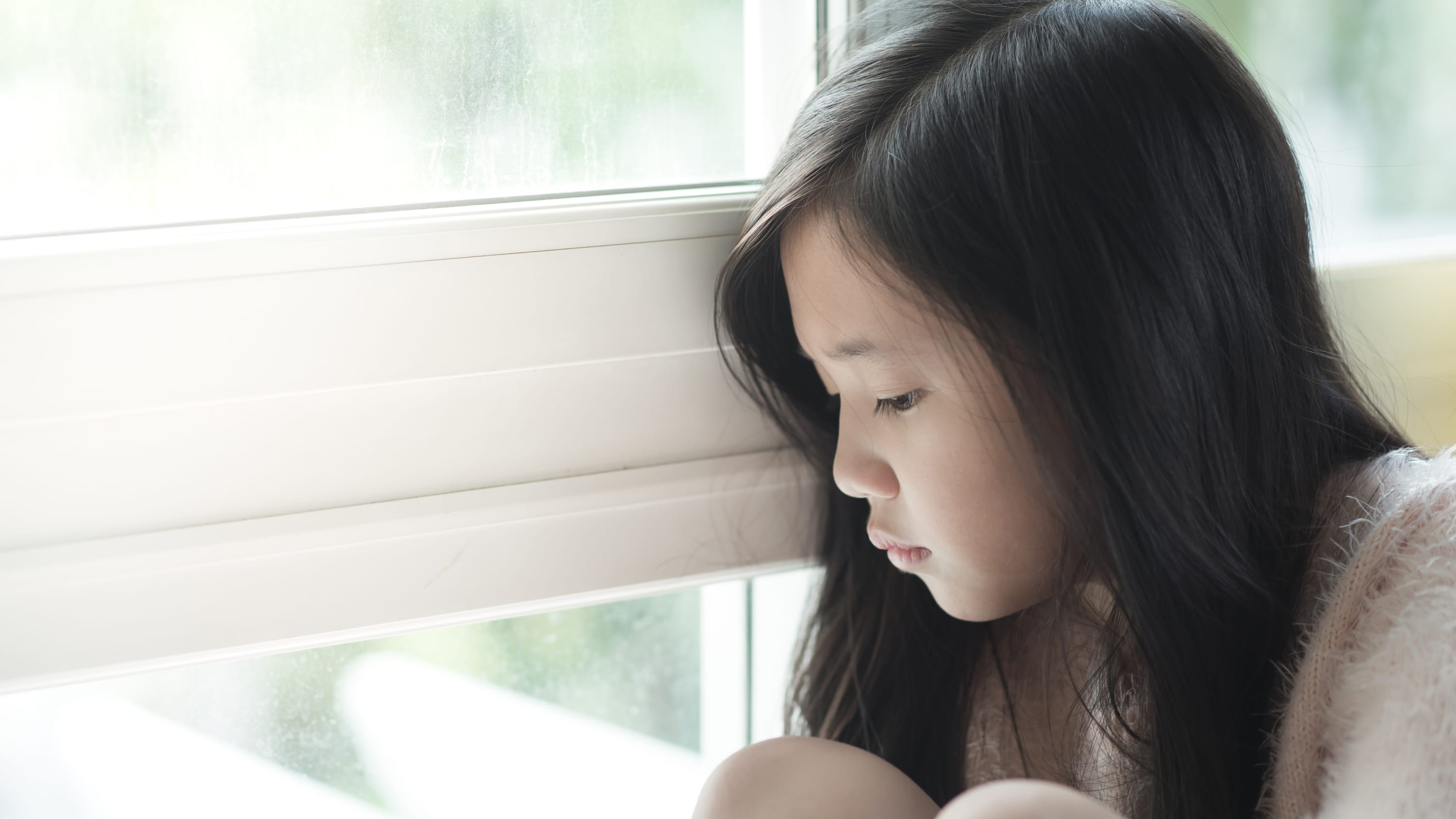A child who may need a pediatric kidney transplant sits by a window