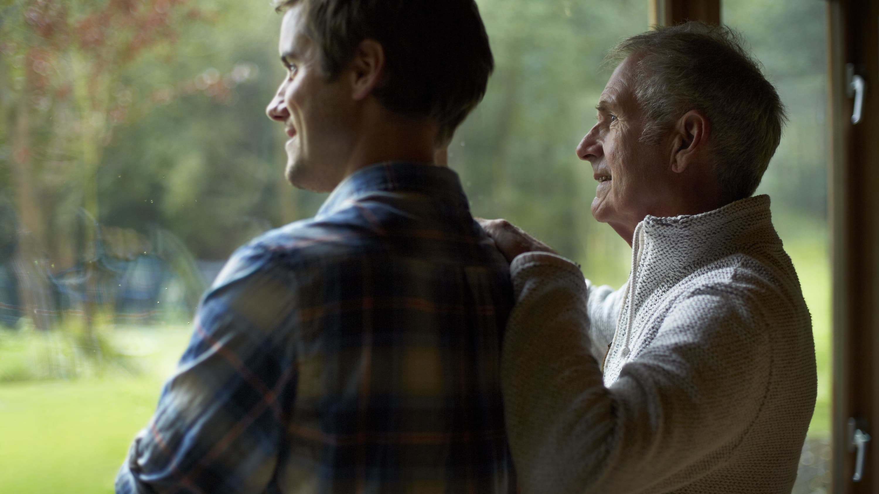 father and song looking out window thoughtfully after stomach cancer diagnosis