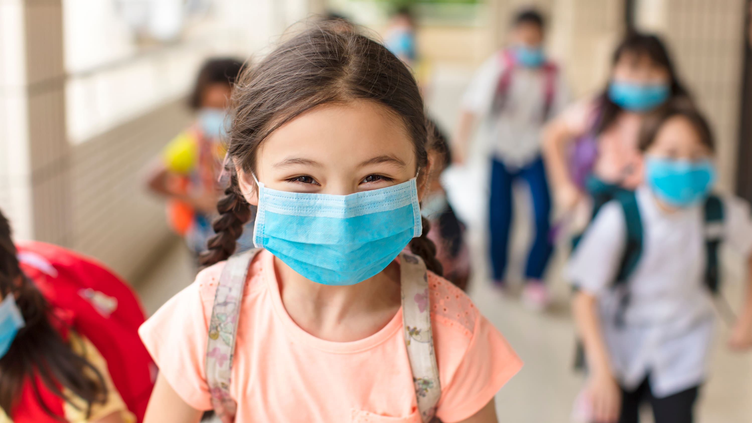 child in mask at school, protecting herself from COVID-19