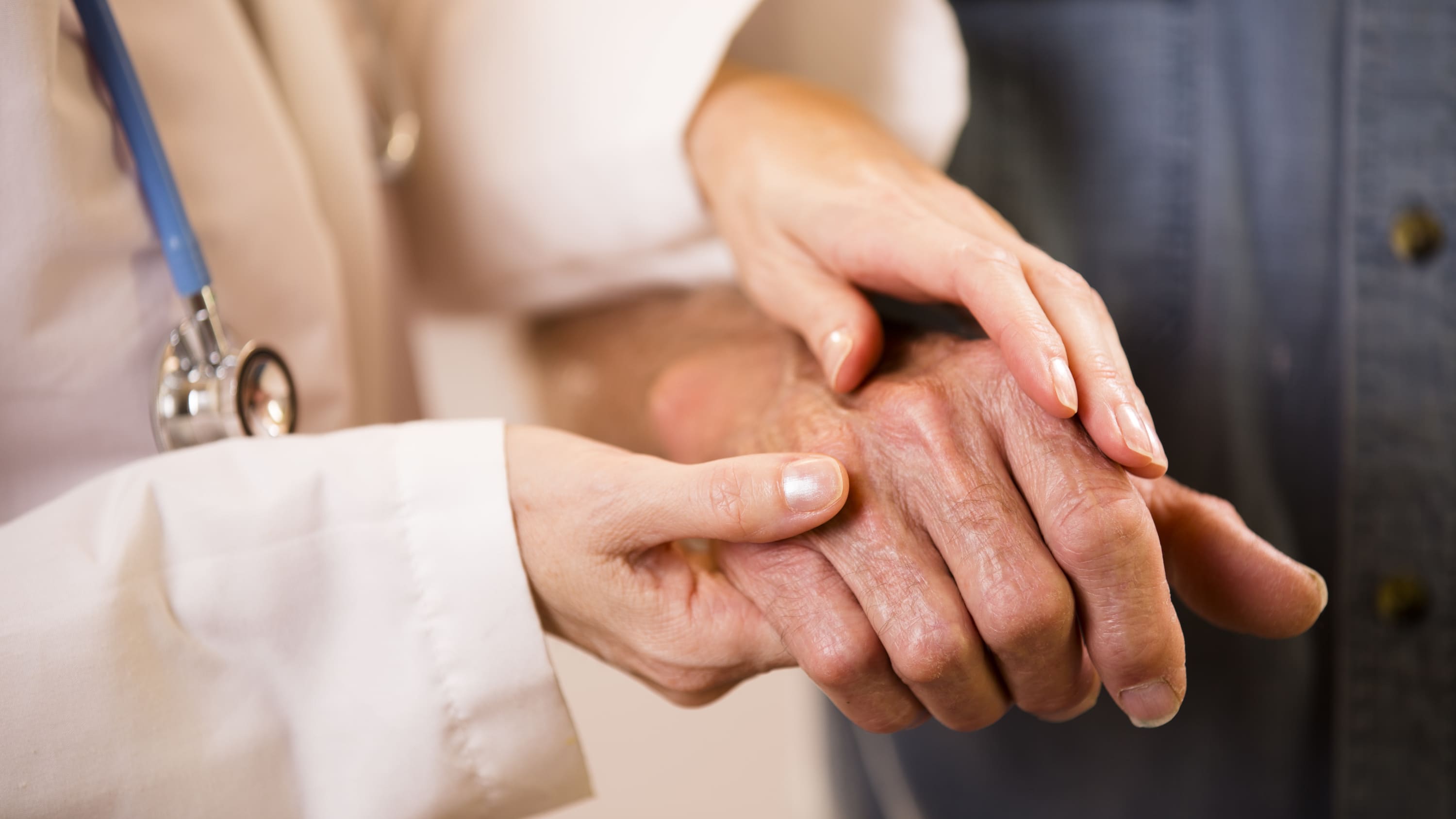 A woman touches a man's hands, someone who possibly has rheumatoid arthritis