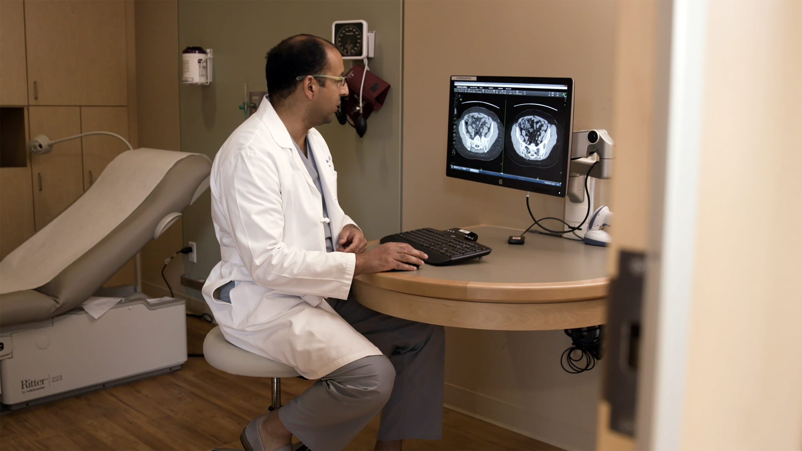A doctor examines two different types of CT scans in a clinic.