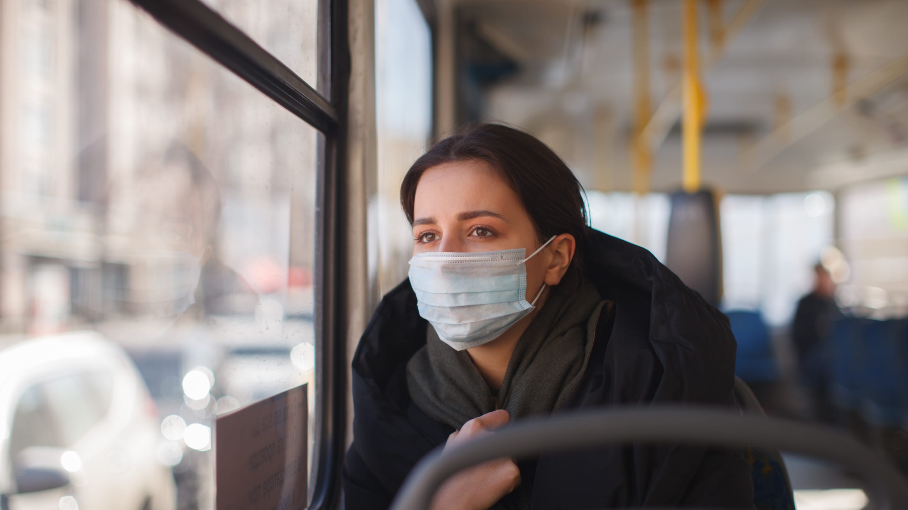 woman with facemask on a bus, worried about Omicron transmission