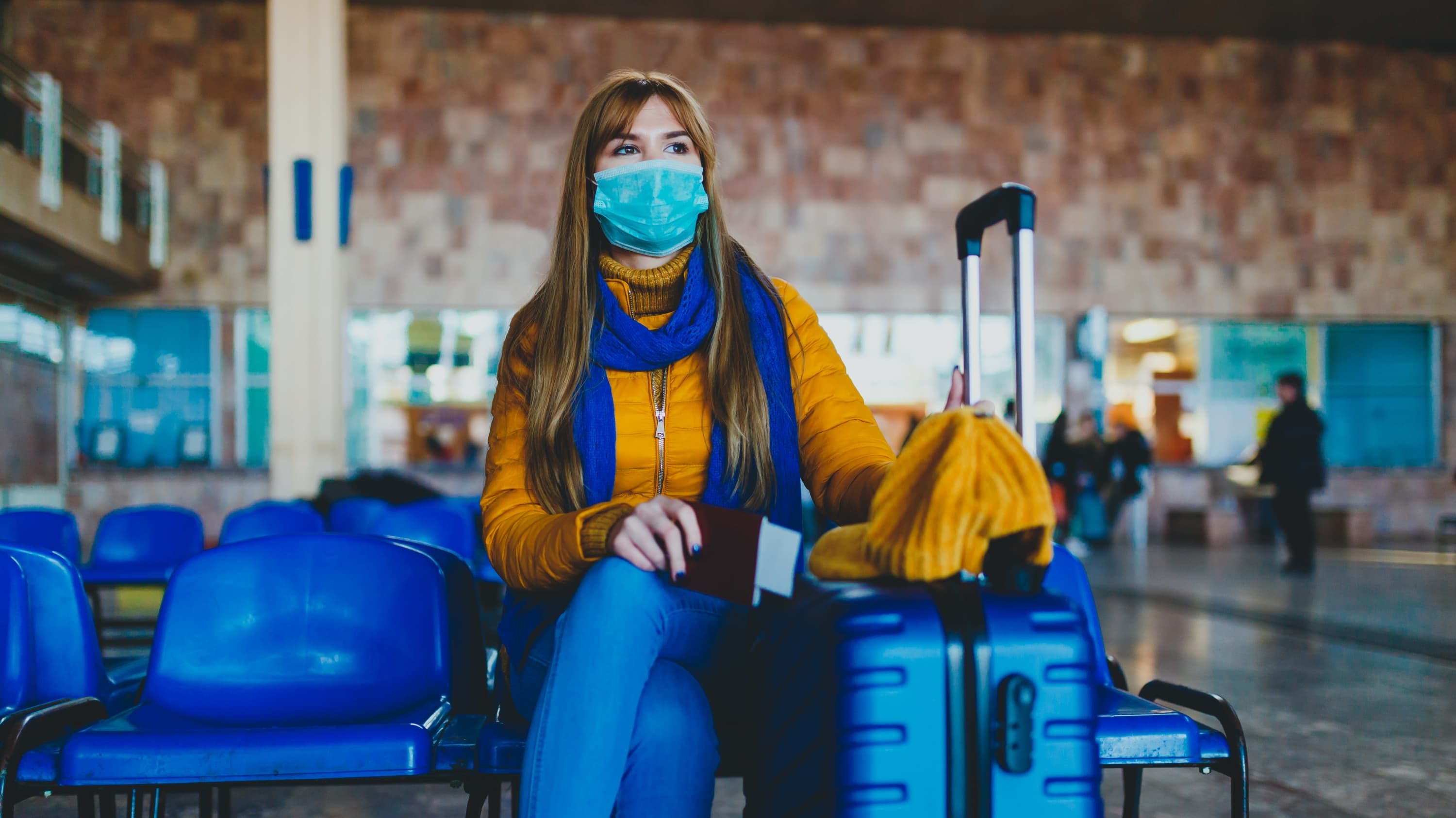 woman in mask at airport, following CDC guidelines for COVID-19 infection prevention