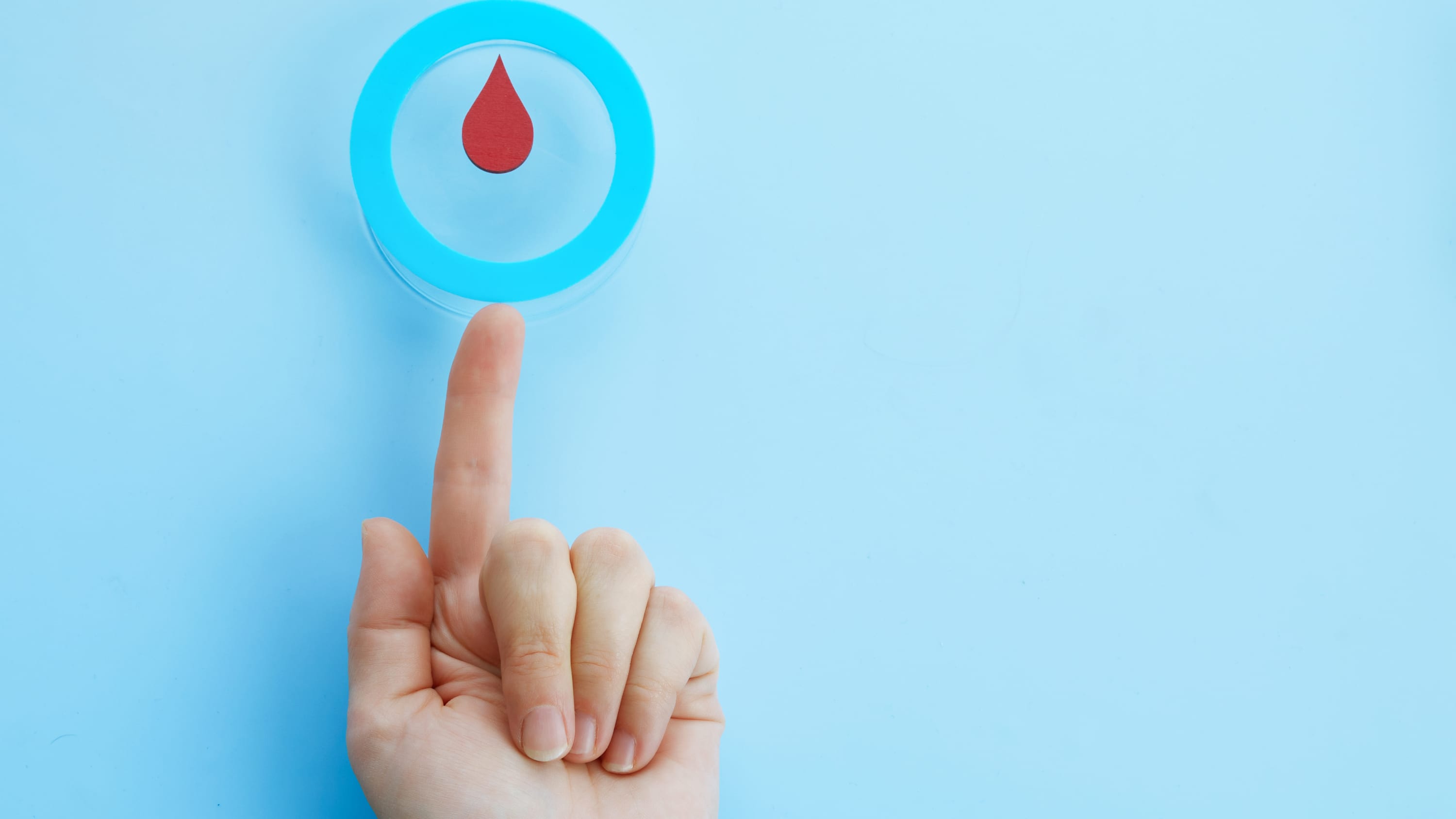 Woman hand with a blue circle with blood drop, symbol of diabetes