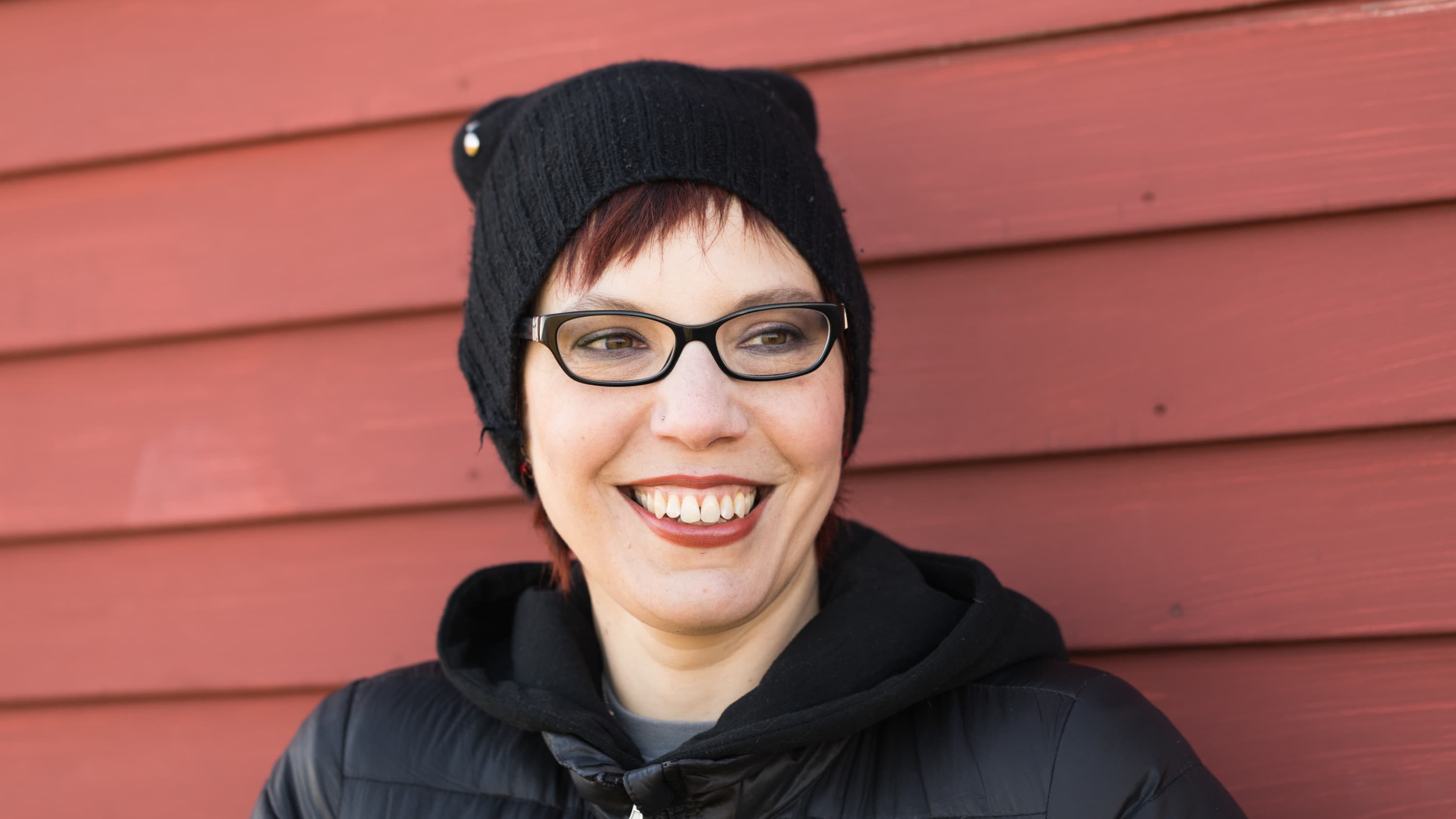 Erika Lewis, with glasses and knit hat, smiles into the camera.