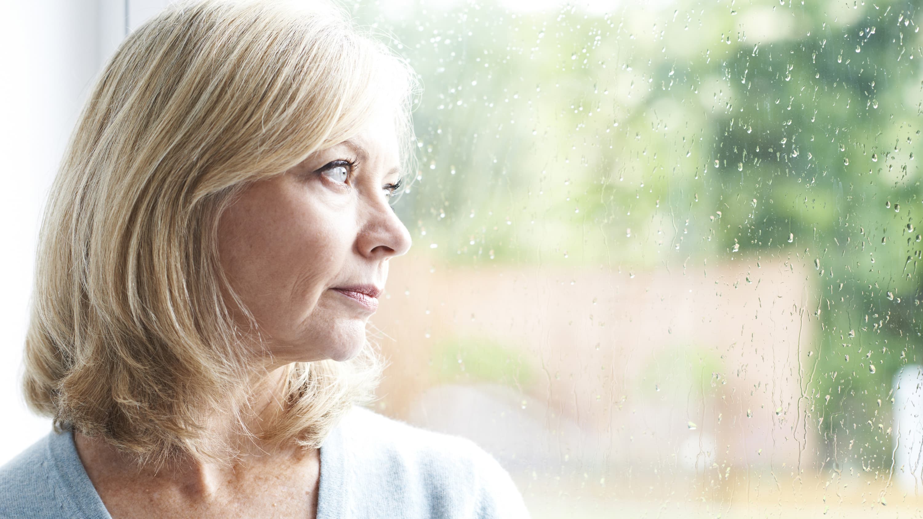 Mature woman who has Wilson disease gazing out a window.