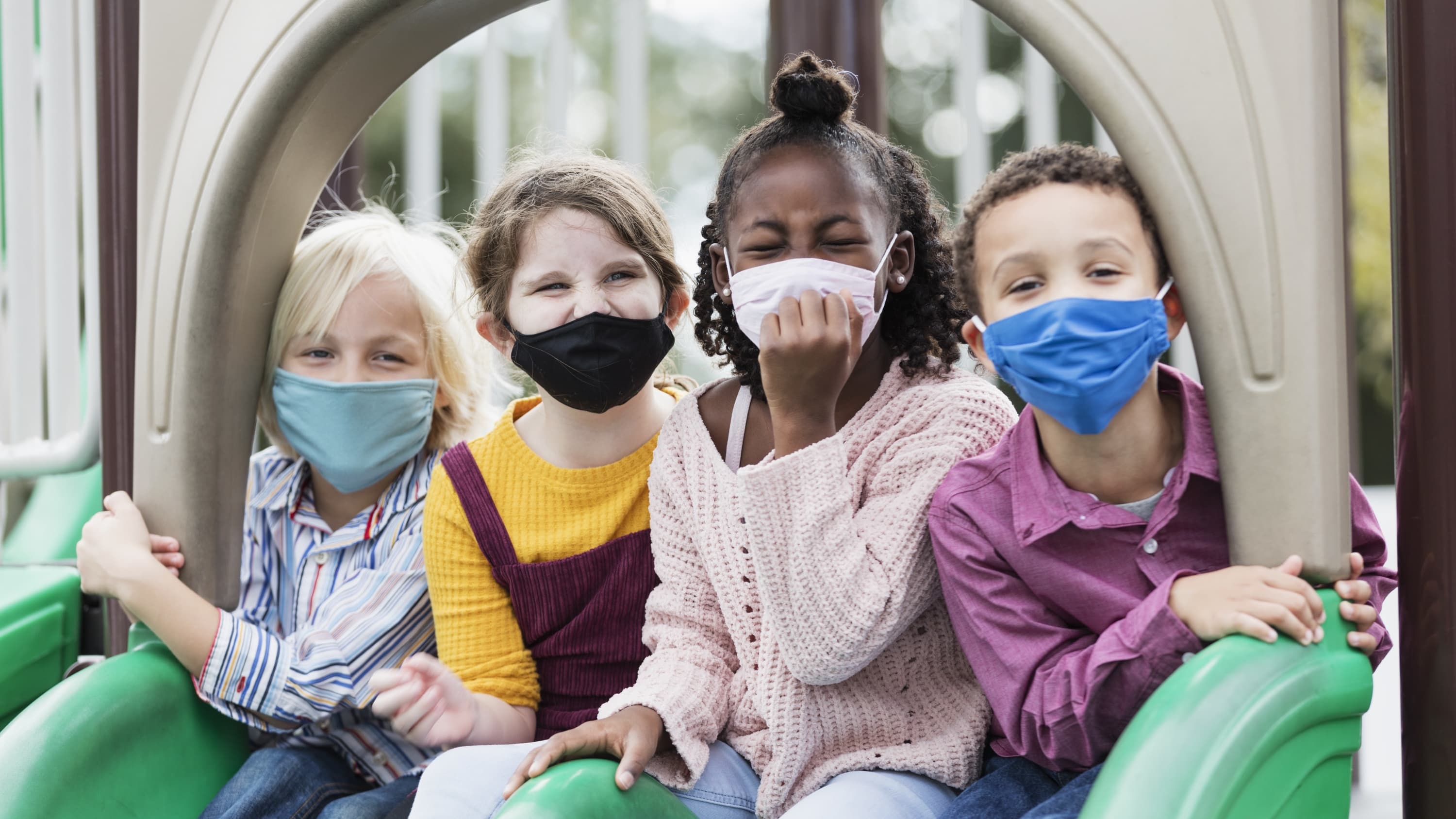 masked kids in a playground who might benefit from COVID-19 vaccine clinical trials