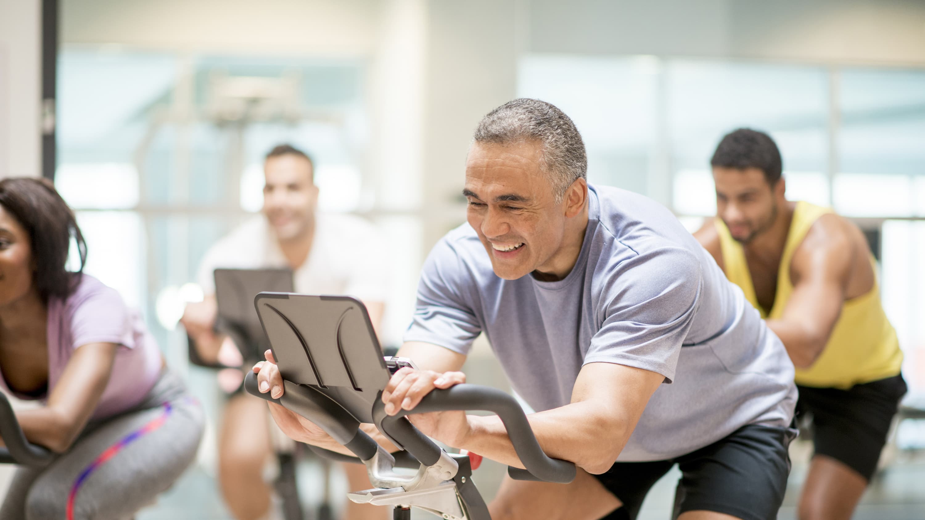 A middle-aged man is back in the gym on the exercise bike after treatment for coronary atherosclerosis.