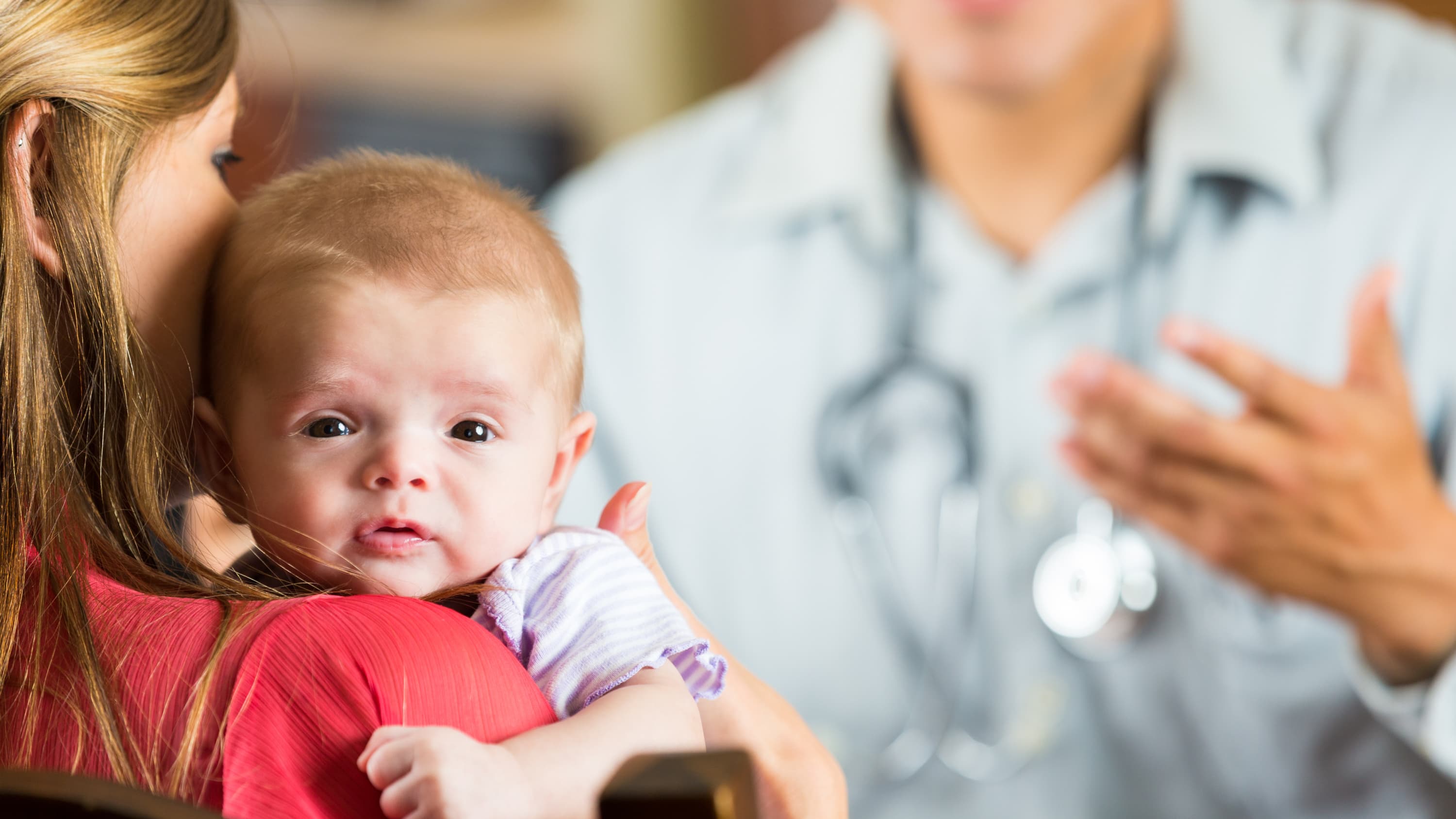 A baby with cystic fibrosis is comforted during a visit to the doctor.