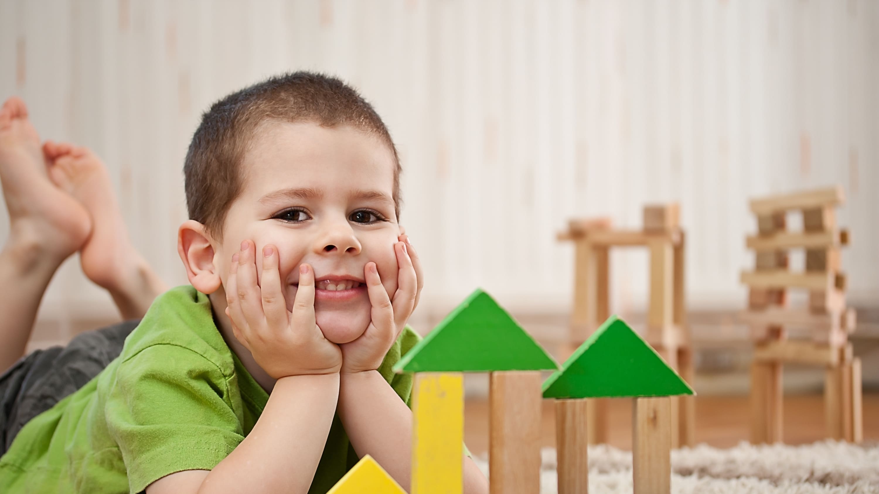a young child sits in front of his wooden block tower, possibly waiting for an appointment to discuss developmental delay