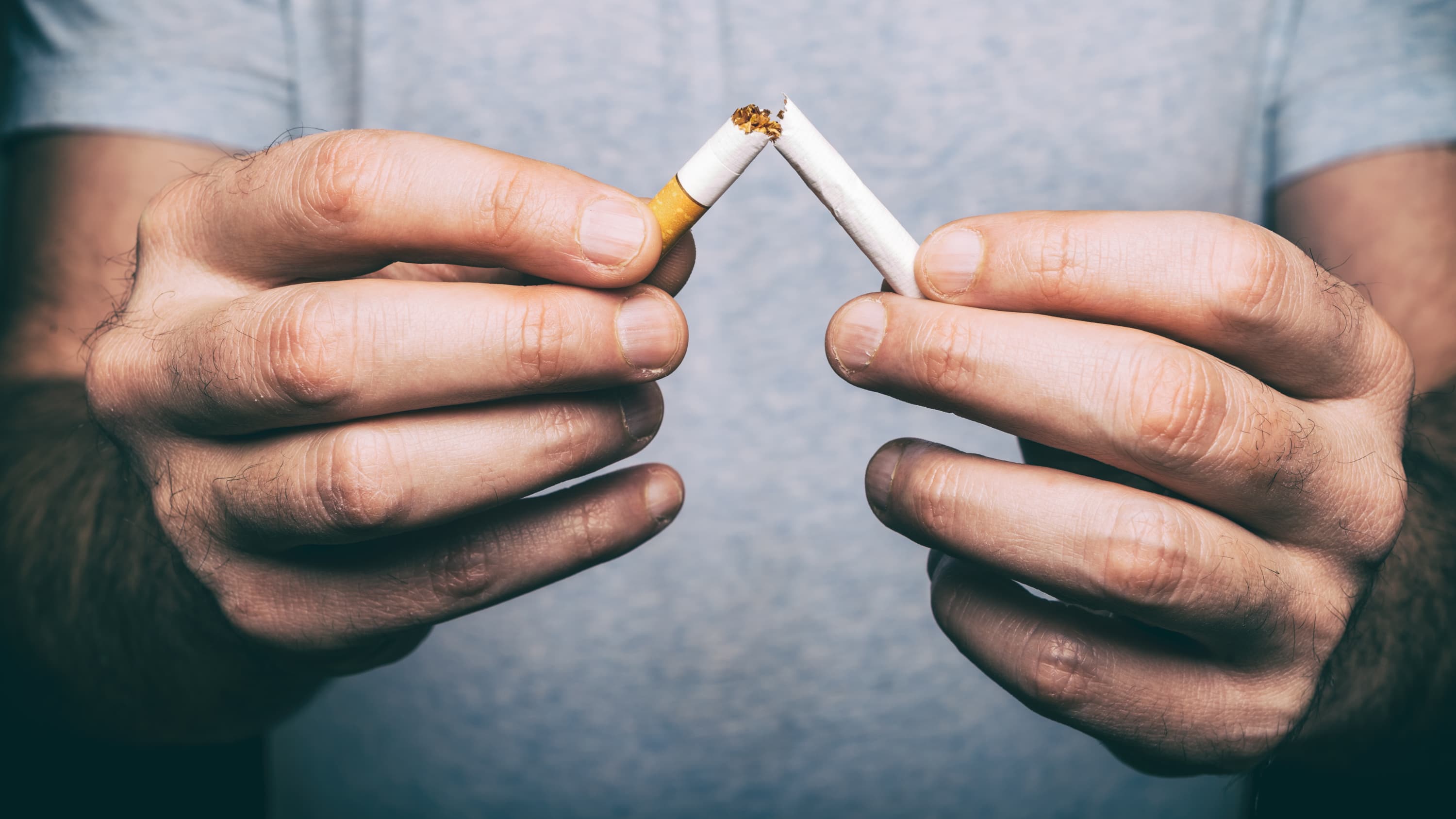 A man holds a broken cigarette. Resources exist at Yale Medicine to help smokers quit smoking.