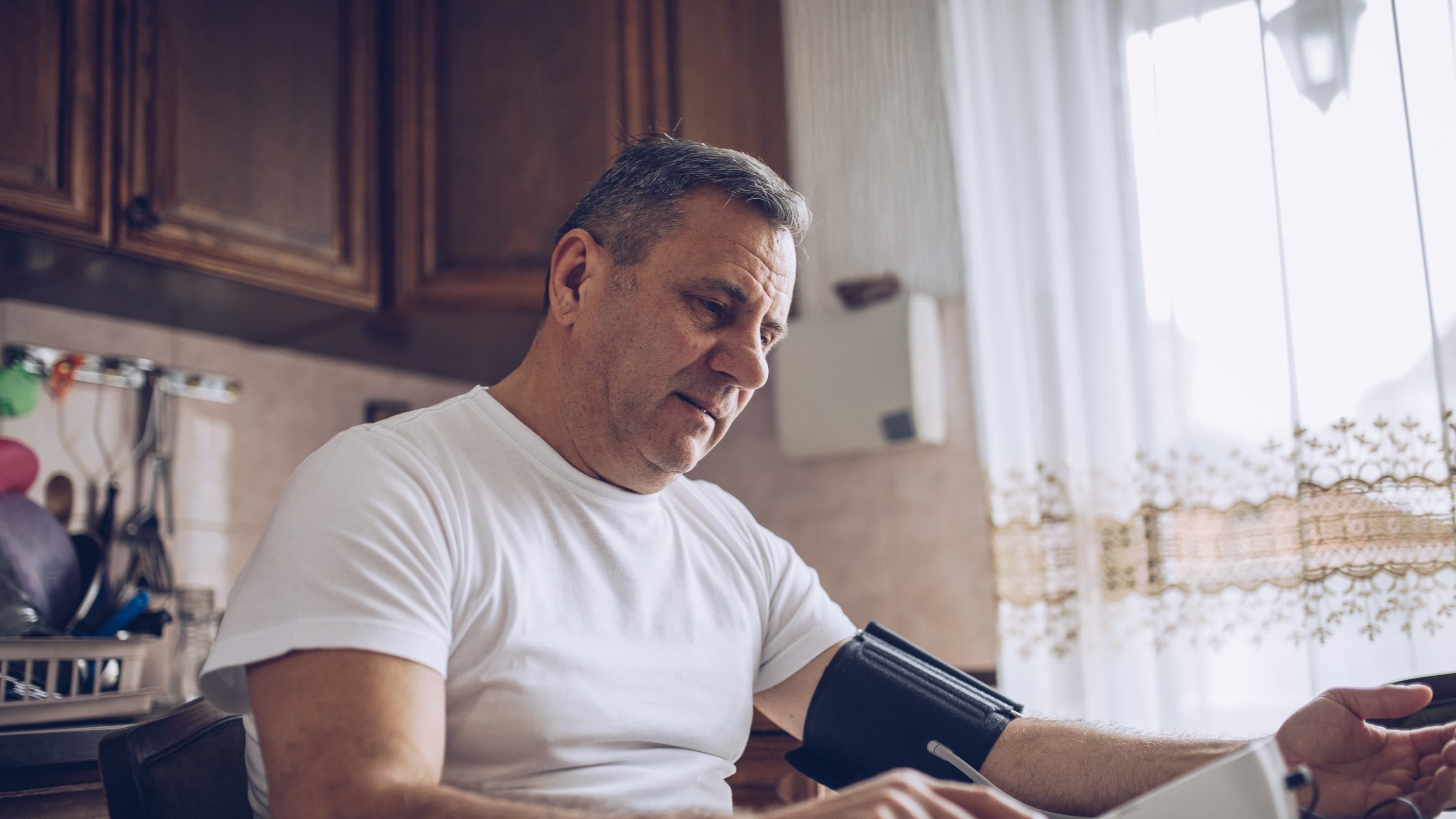 Man taking his blood pressure at home, afraid to go to the ED because of potential COVID-19 infection