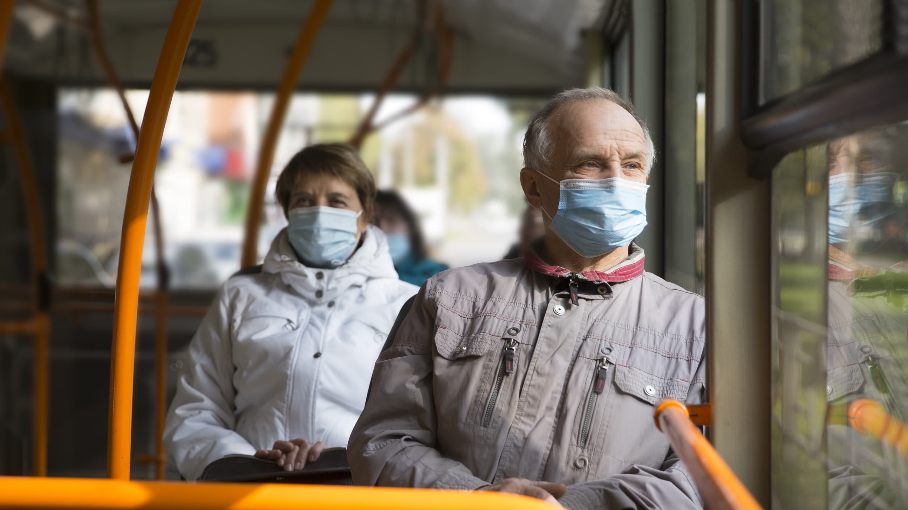 older people at high risk for COVID on a bus practicing strategic masking