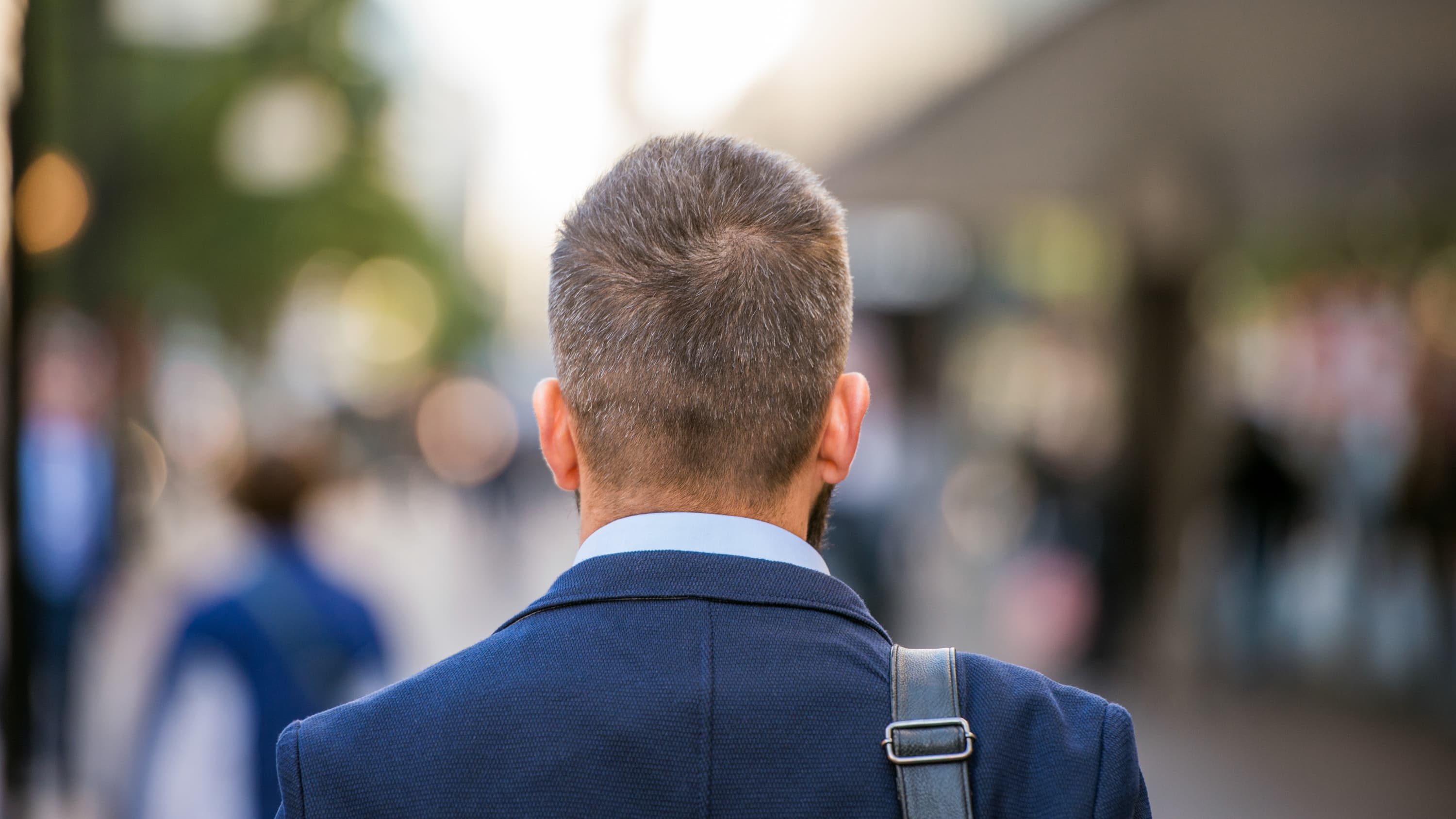 A man with a pituitary tumor walks down a crowded sidewalk.
