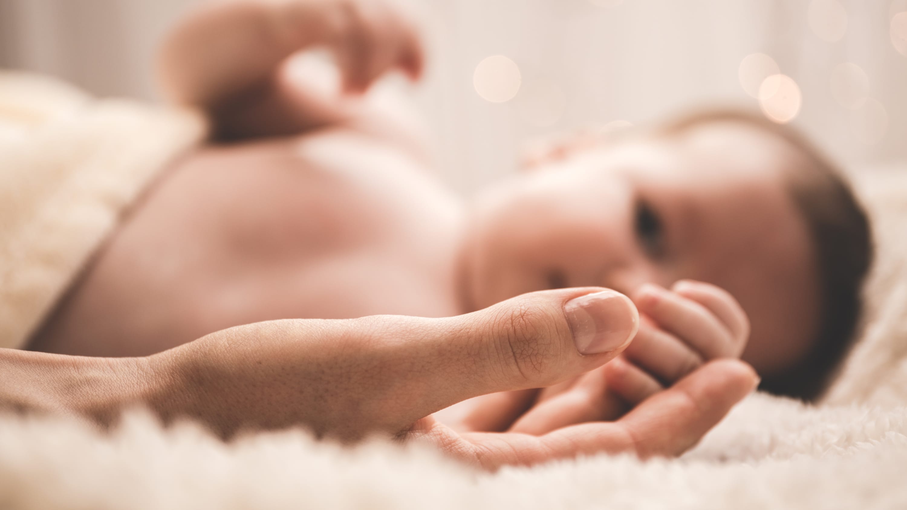 An infant that has pediatric reflux disease reaches for its mother's hand
