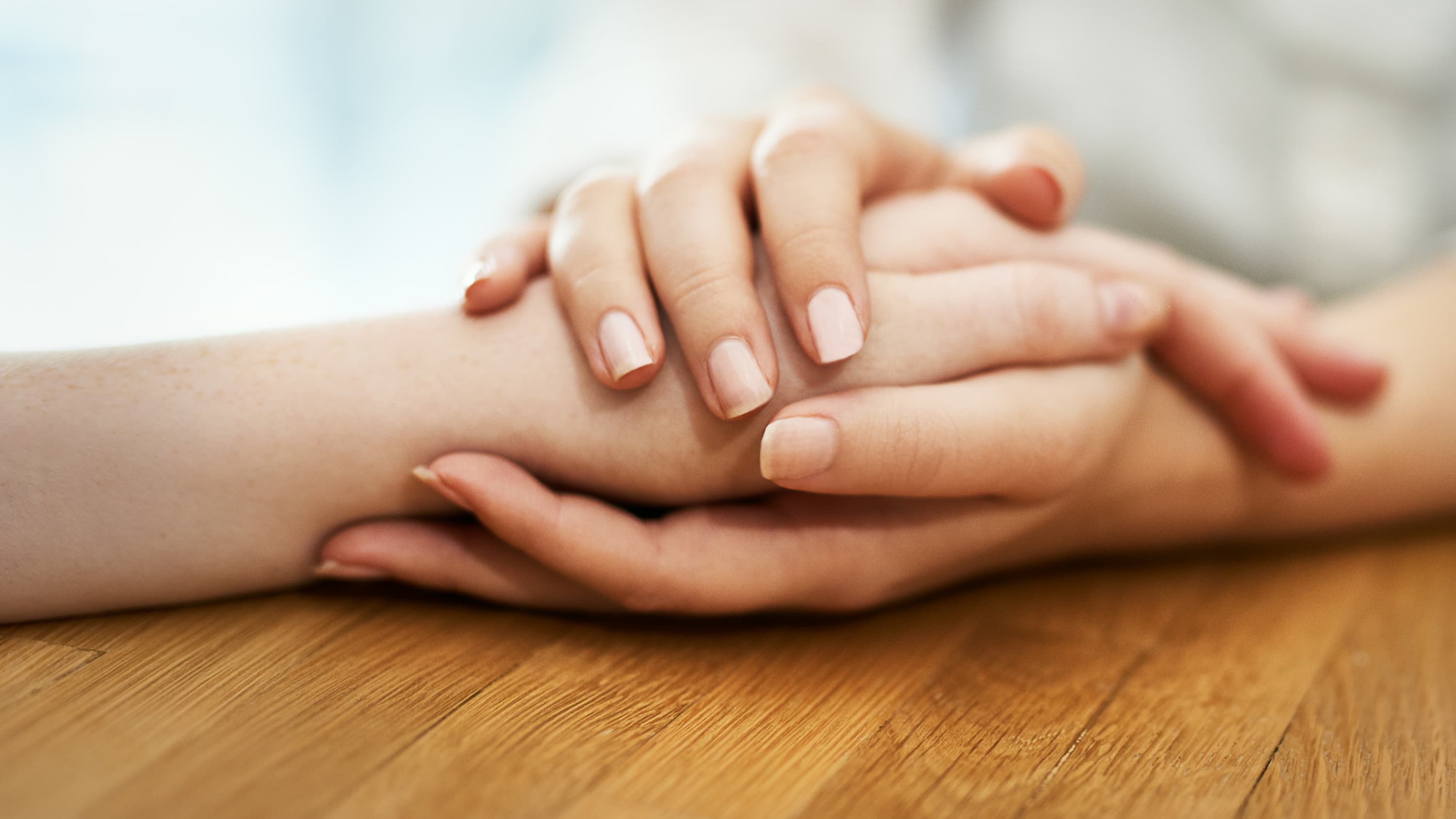 A patient is comforted by a family member holding her hand possibly following a skin lymphoma diagnosis.