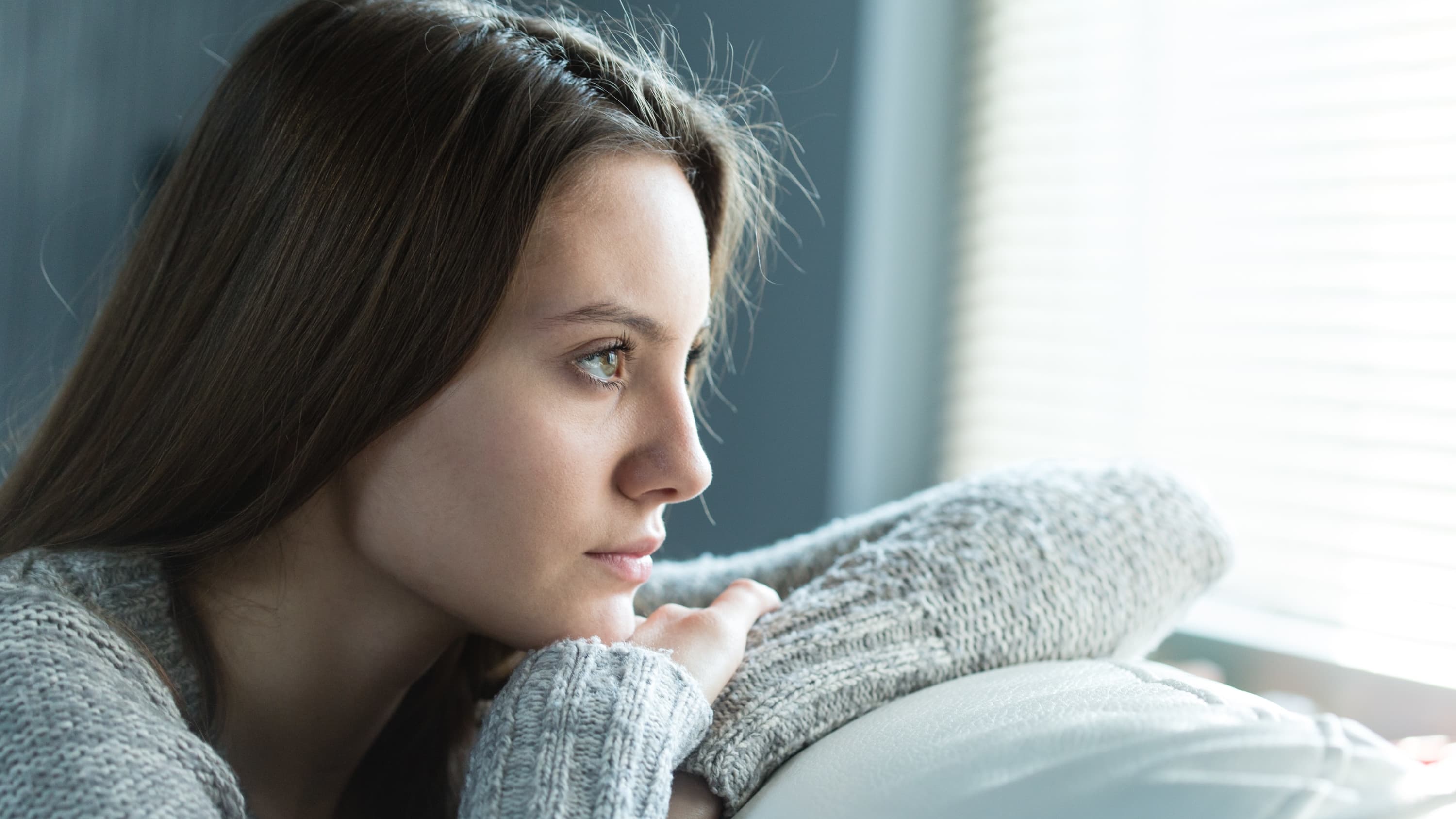 woman looking out window, possibly worried about vaginitis