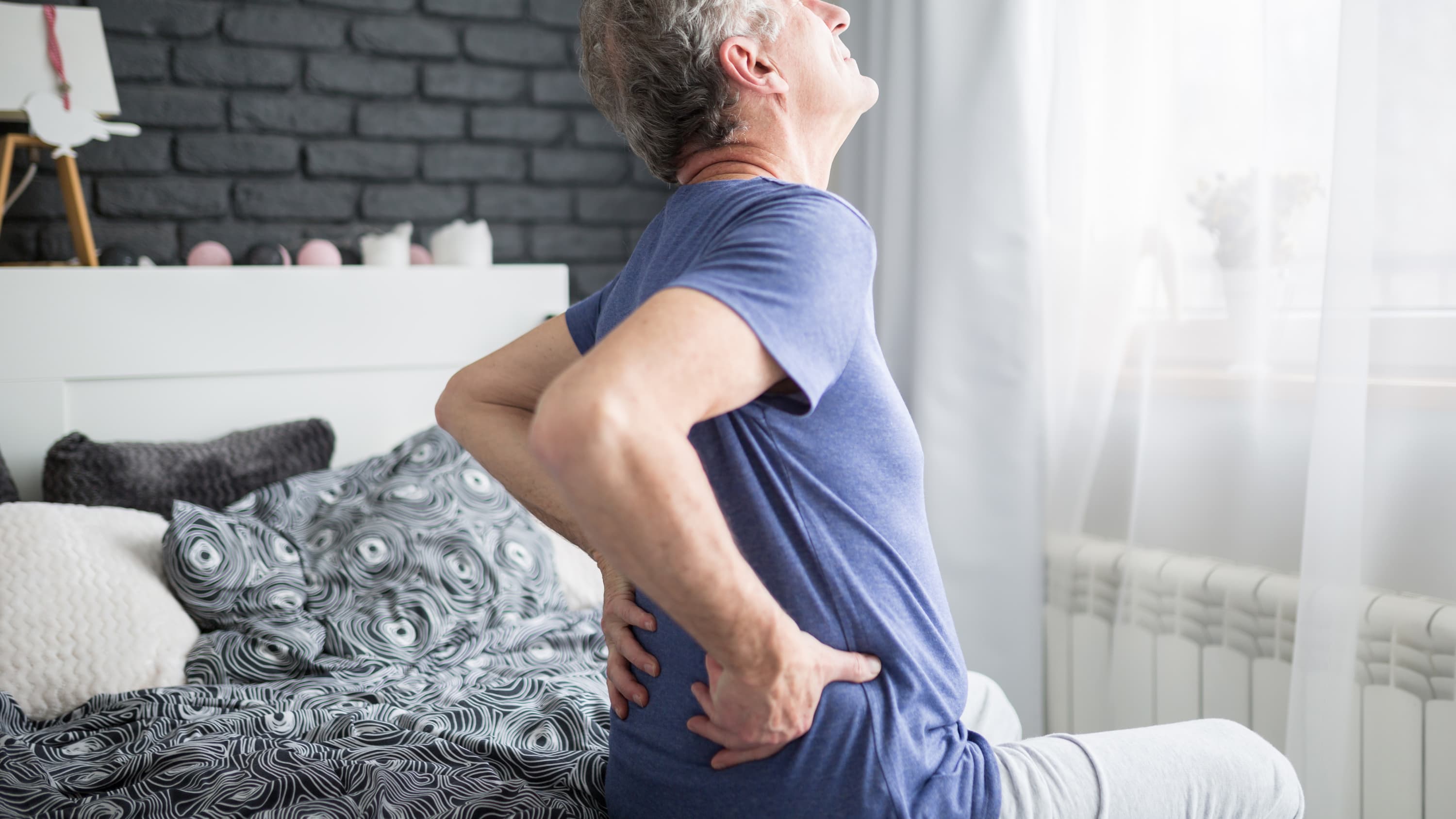 A man suffering from glomerulonephritis grabs his lower back in pain.
