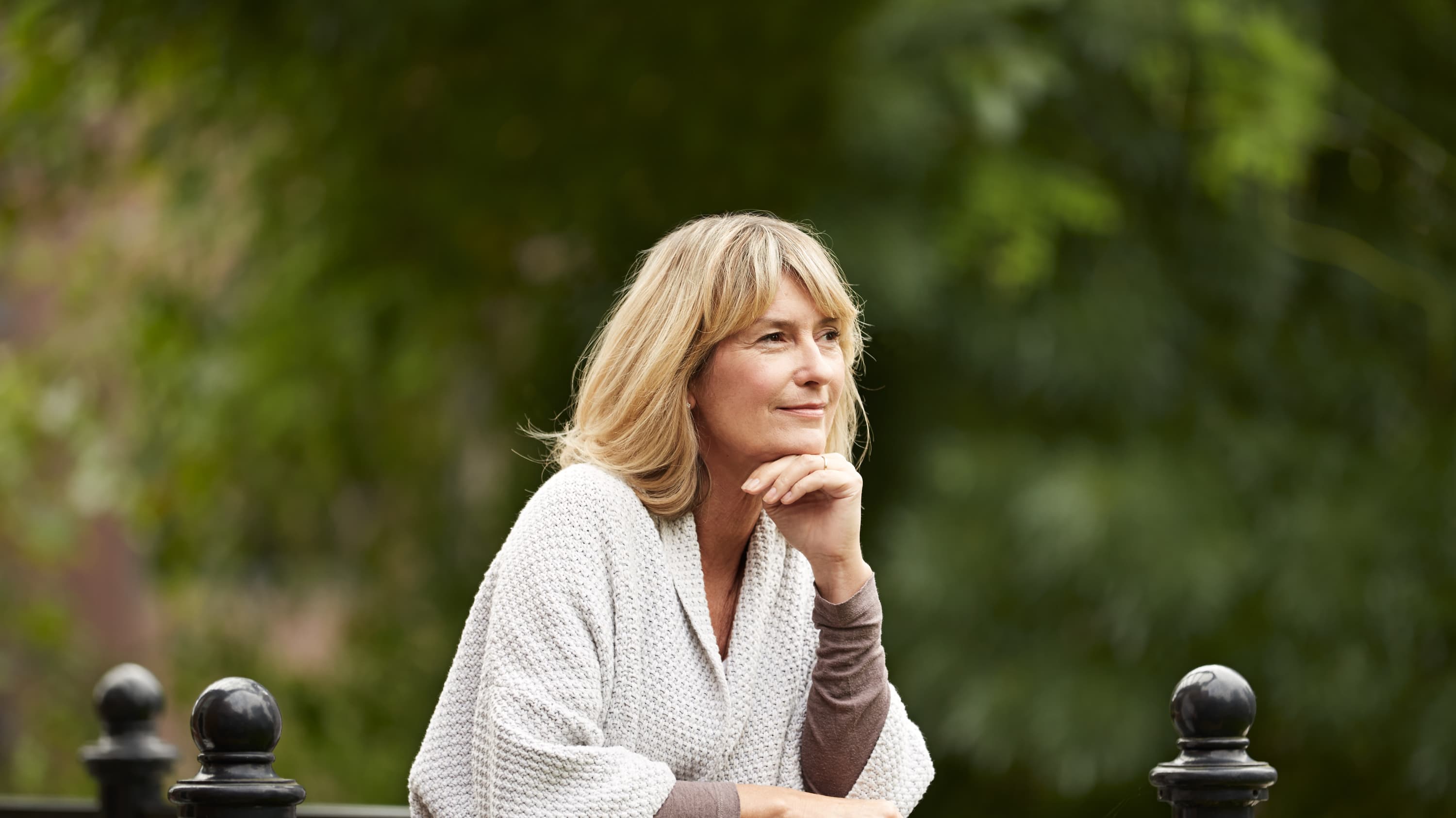 A middle-aged woman gazes out above her balcony, deep in thought, possibly about low bone density