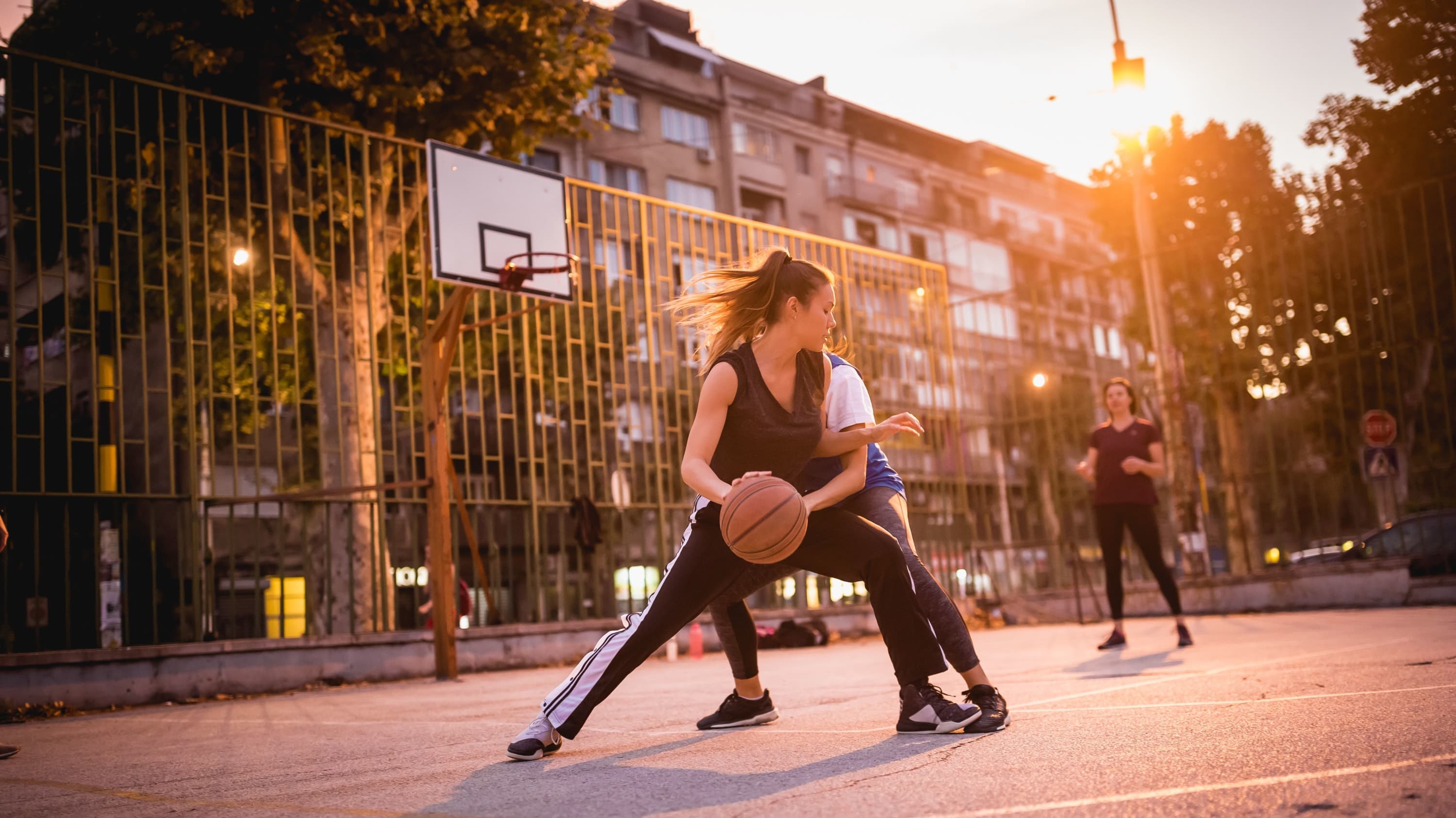 two women playing basketball outside, demonstrating how a meniscus tear—and need for meniscus transplantation—can occur