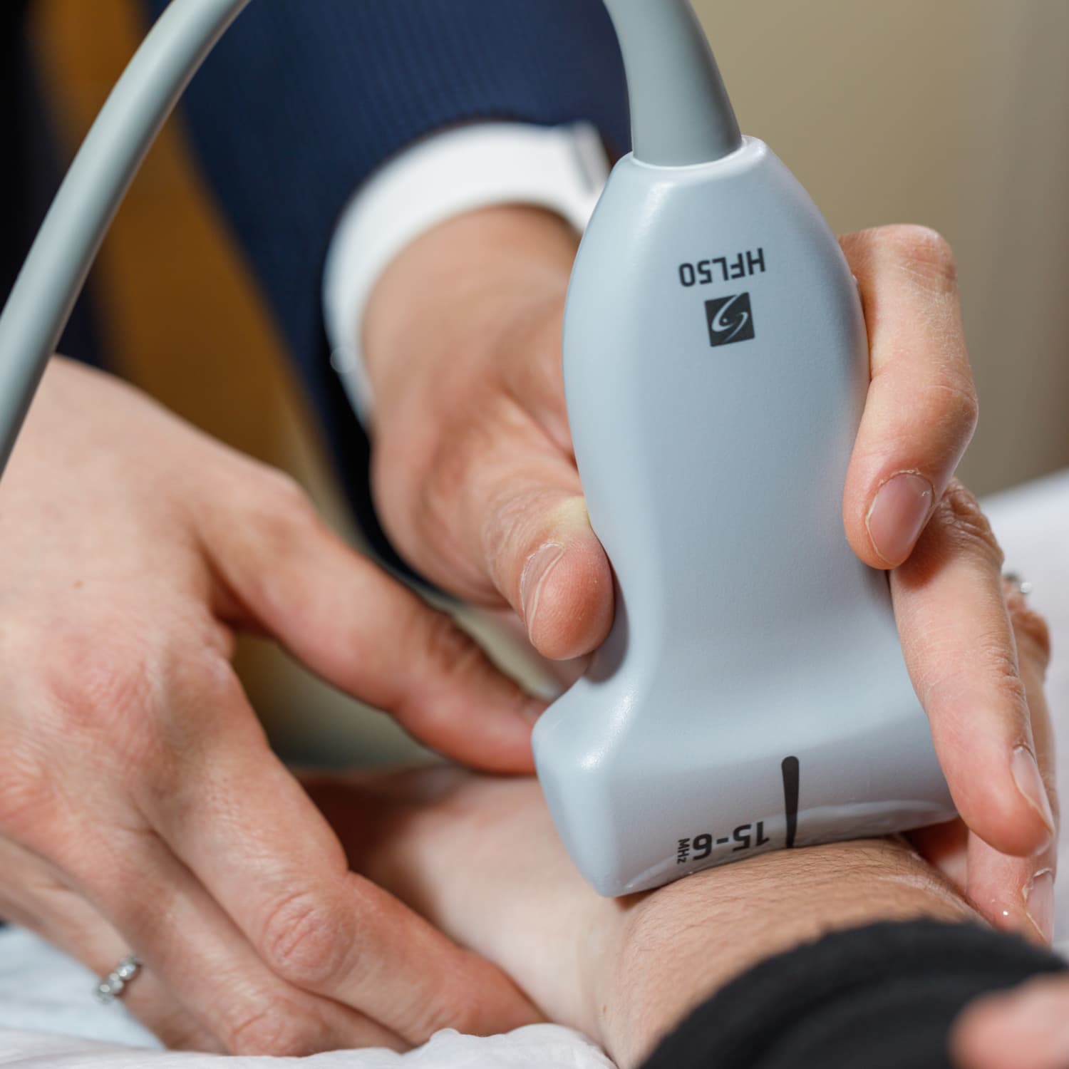 Medical illustration showing a hand holding an ultrasound machine