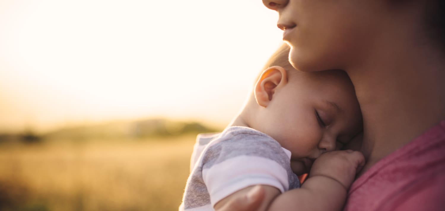 A woman holds her napping son.