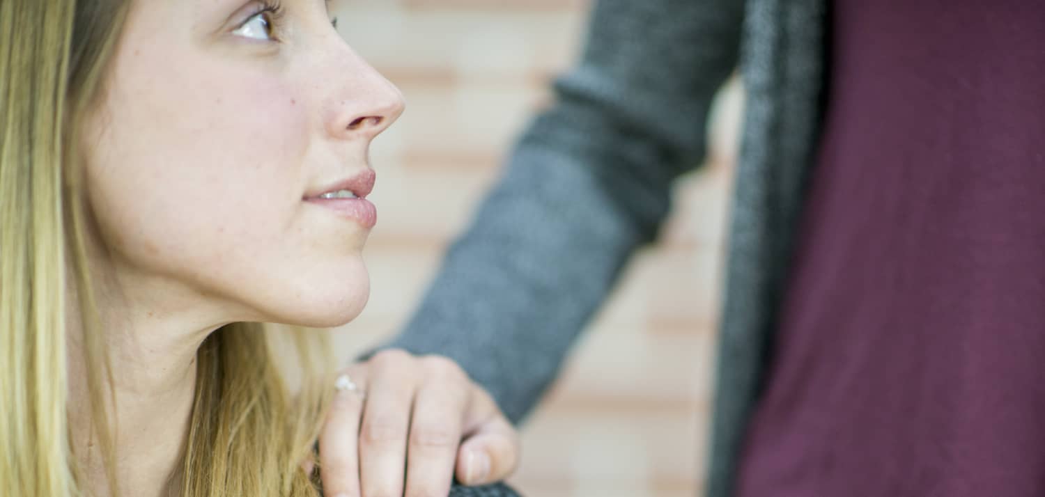 A person puts her and on the shoulder of a woman who may be experiencing a psychotic episode.