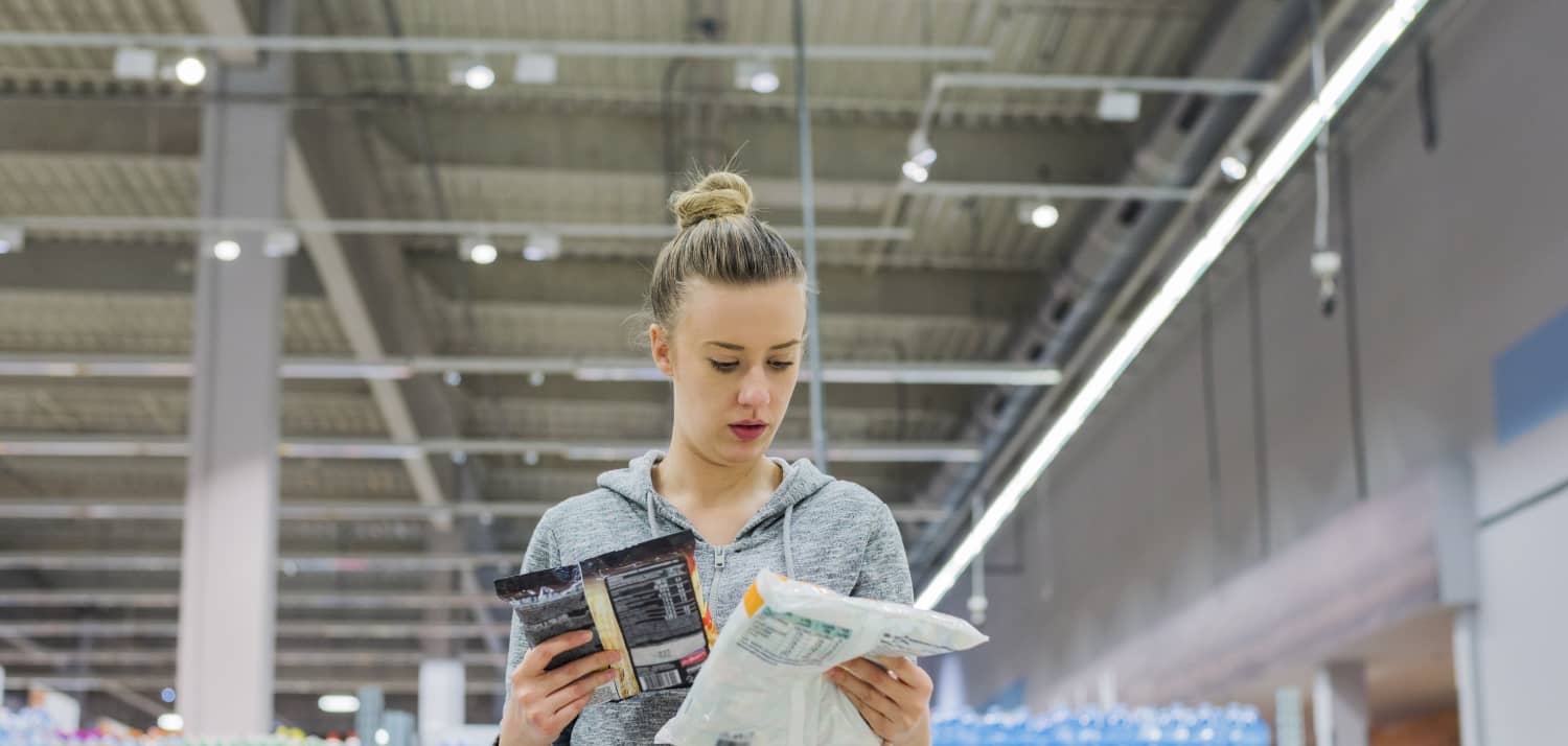 woman looking at food packages in grocery store to see if they're ultraprocessed