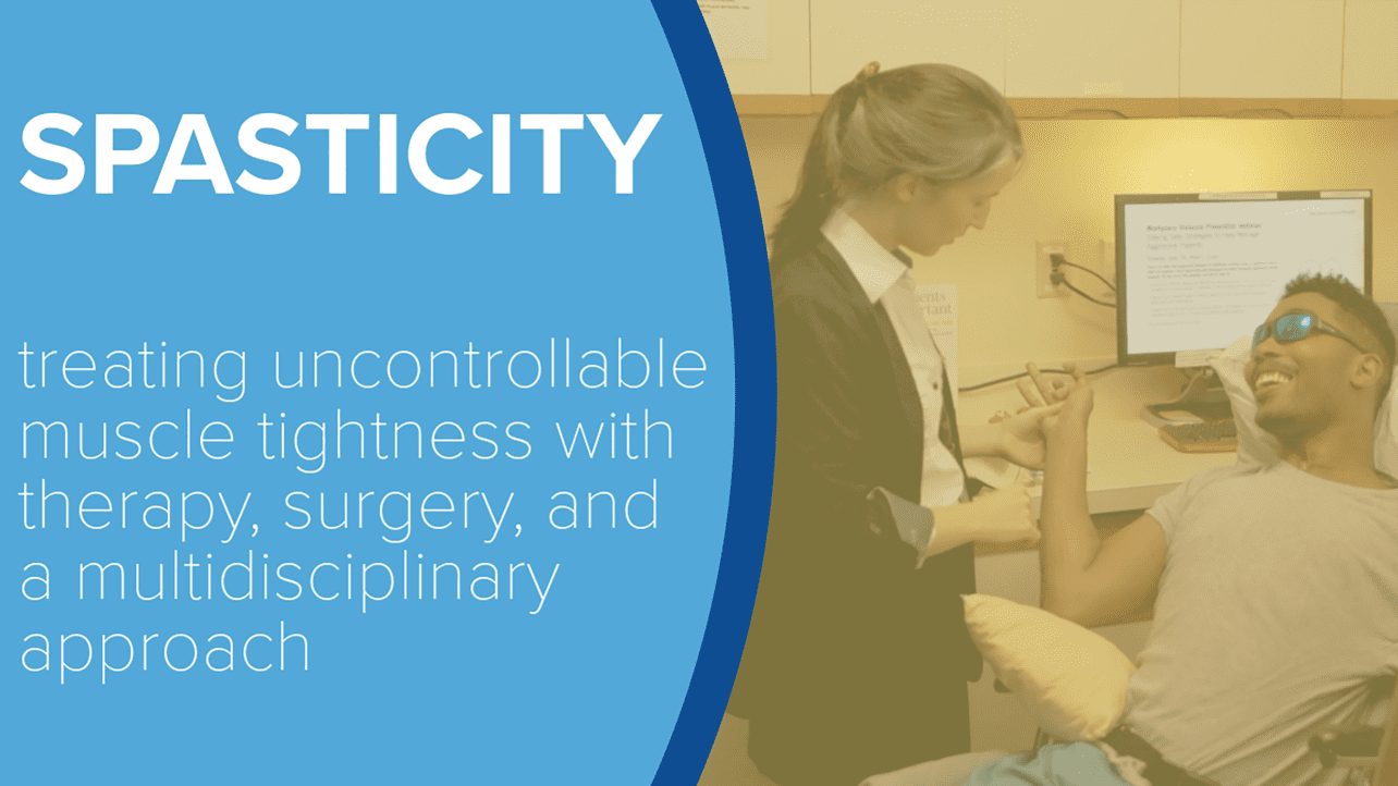 A black male patient with spasticity smiles as his arm is examined by a white female physician