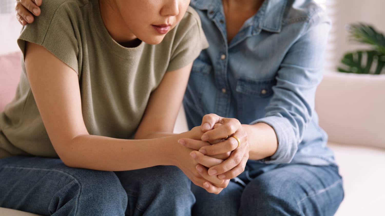 A woman holds the hands of a young girl who may be having a psychotic episode