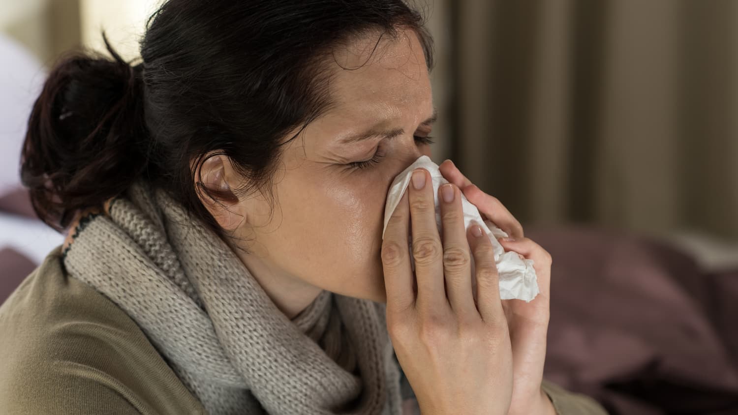 young-sick-woman-sneezing-in-tissue-sweating-from-flu-fever-SBI-300904846