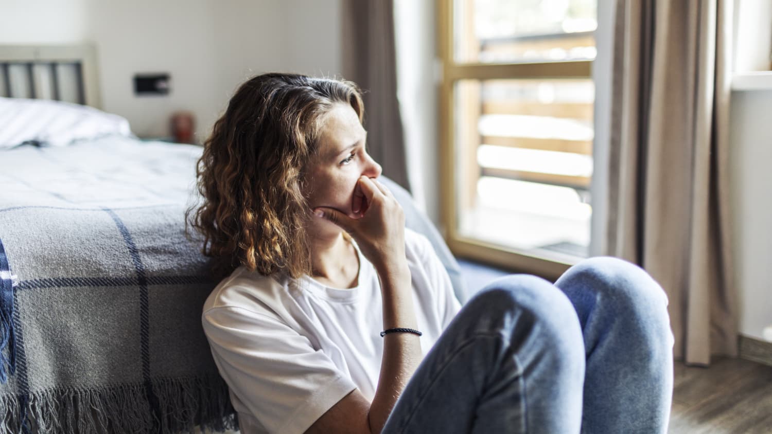 woman with fatigue from irony deficiency sitting on floor of bedroom