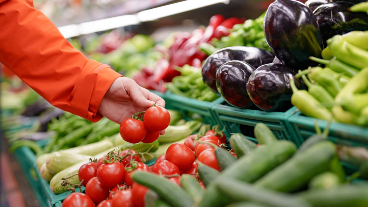 hand reaching for tomatoes, as part of a low FODMAP diet, at grocery store