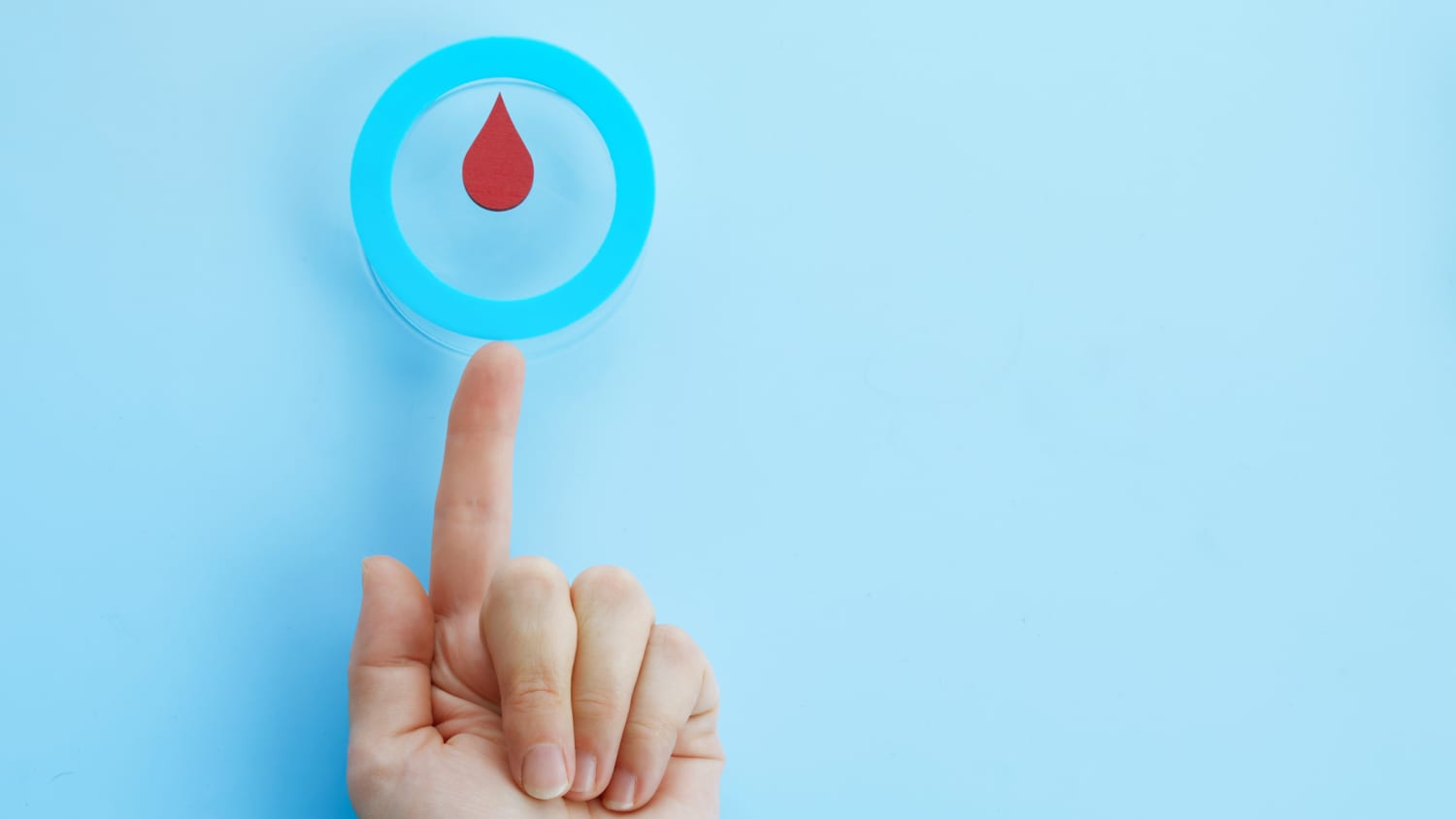 Woman hand with a blue circle with blood drop, symbol of diabetes