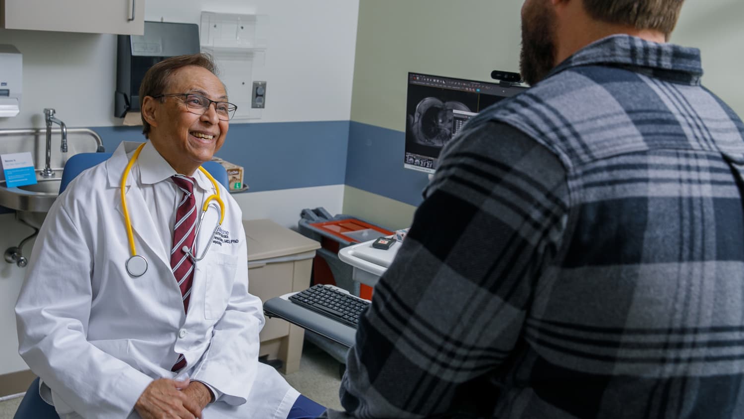 Pramod Mistry, MD, a Yale Medicine physician and Gaucher disease expert, talks to a patient in an exam room.
